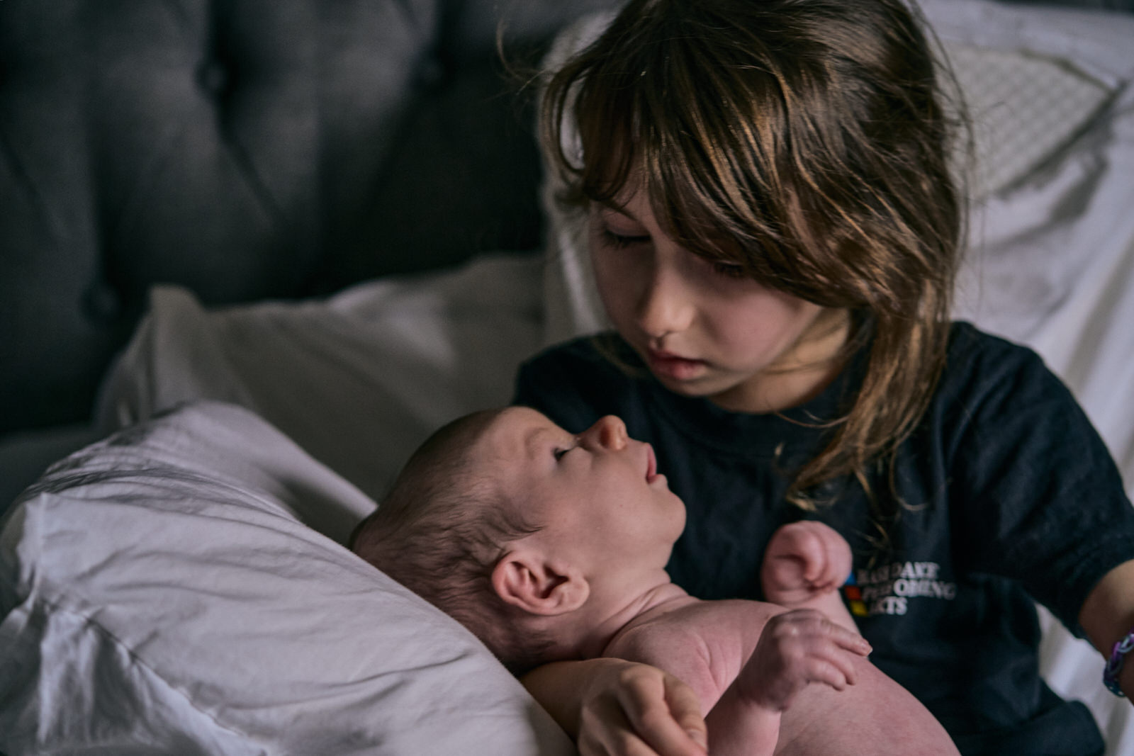older sibling gazes down at new baby brother