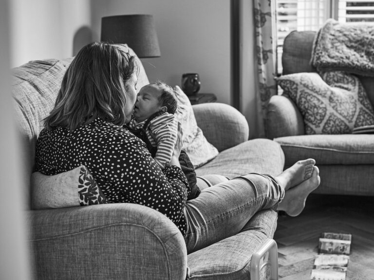 natural photo of mum kissing newborn baby on sofa