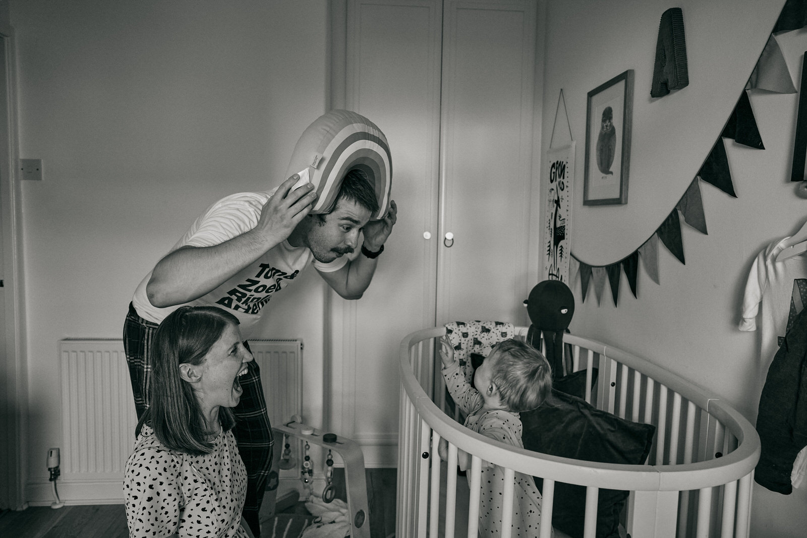 fun photo of dad wearing rainbow cushion to make baby laugh