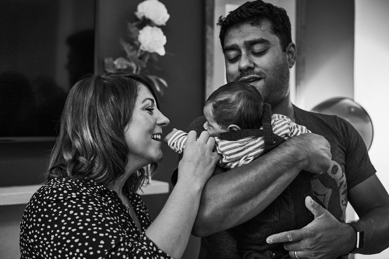 mum smiles and kisses newborn baby hand