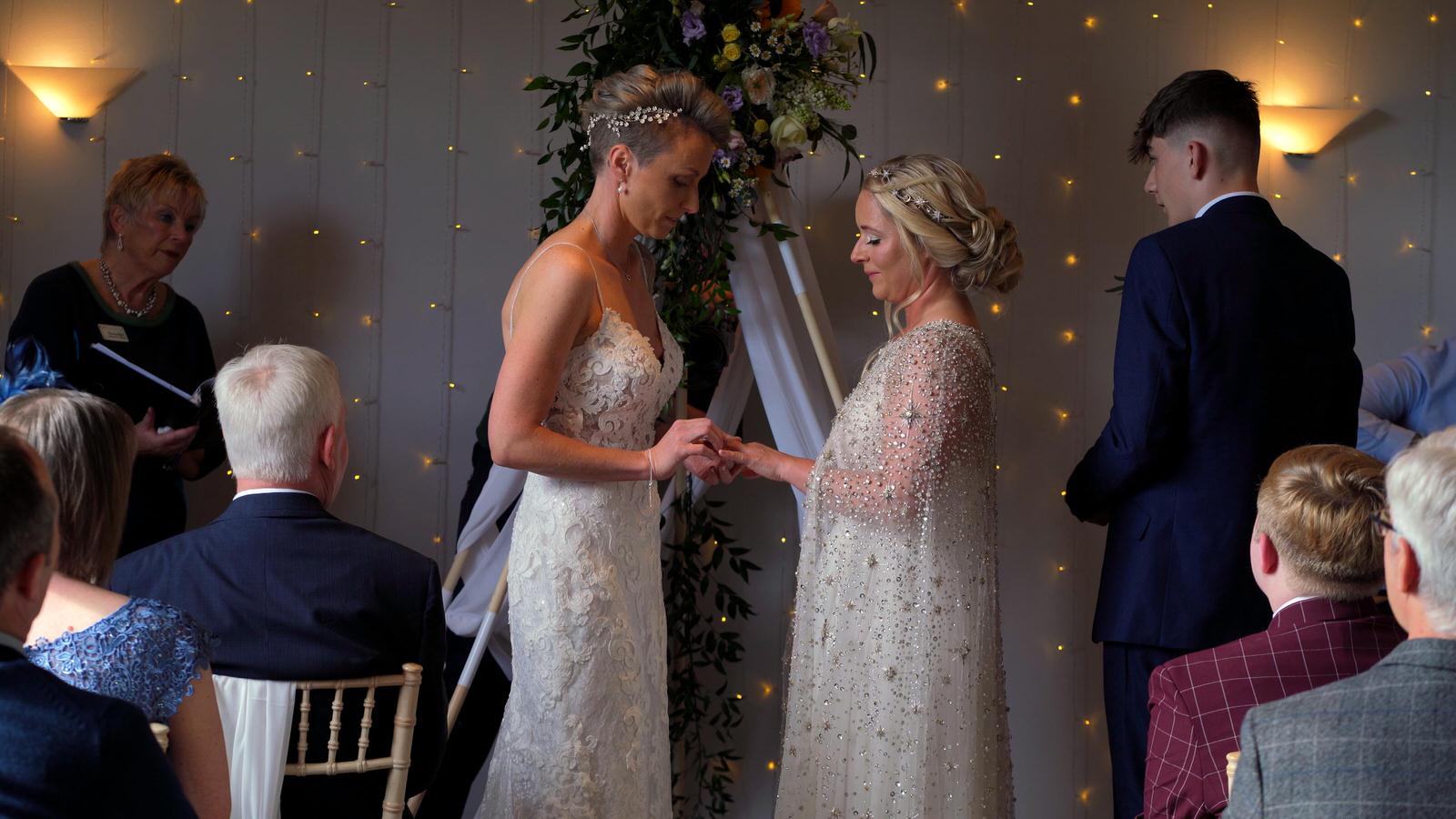 a bride puts a ring on her bride during same sex wedding