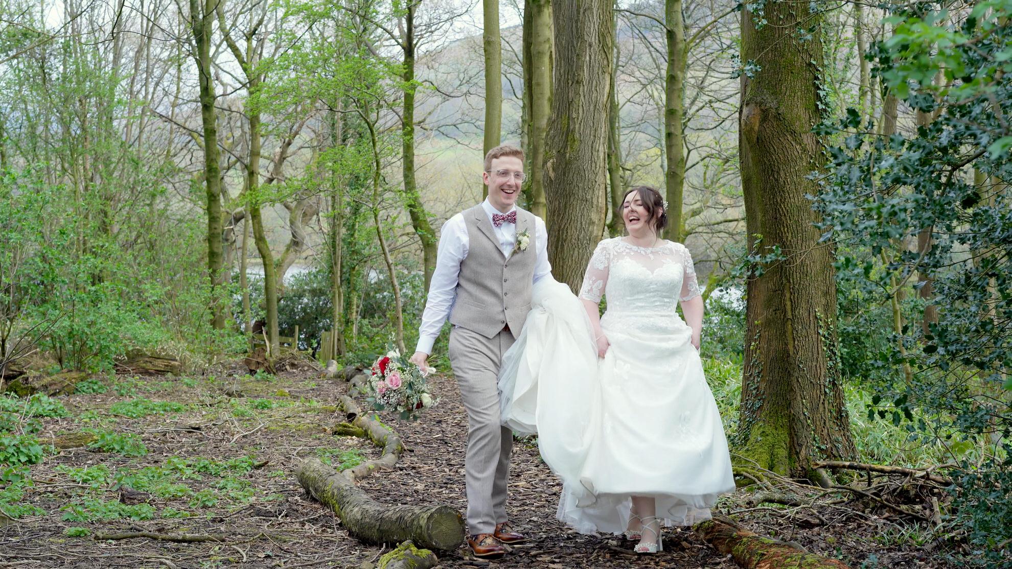 couple walk and laugh for videographer through woods at Wyresdale Park