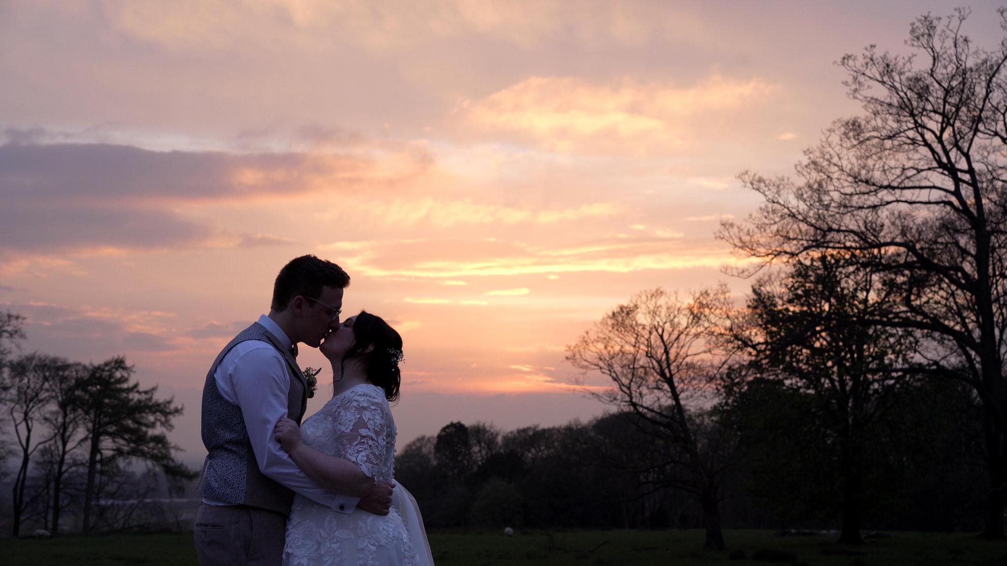 couple stand in front of lancashire sunset for wedding videographer