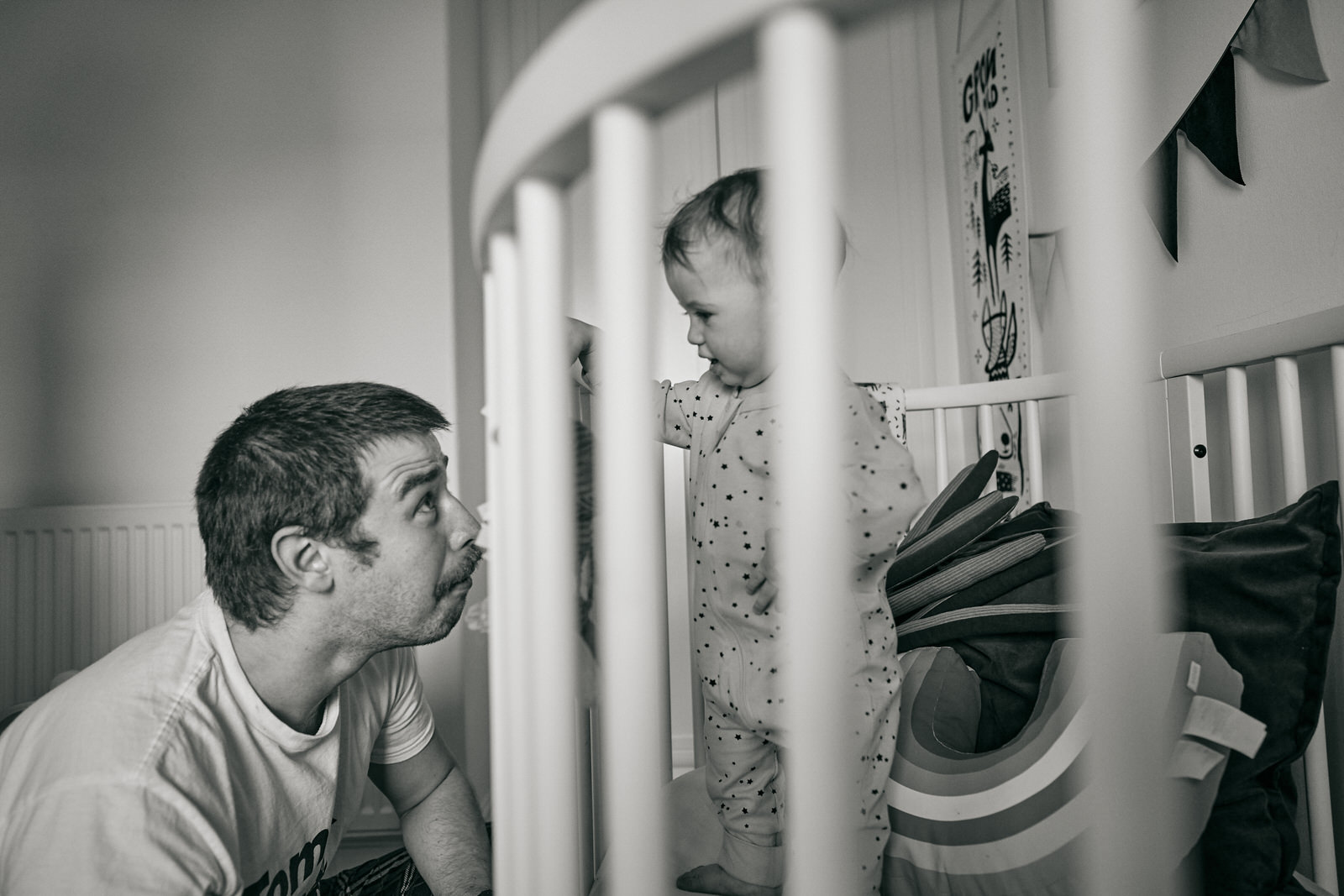 dad playing with toddler in their cot