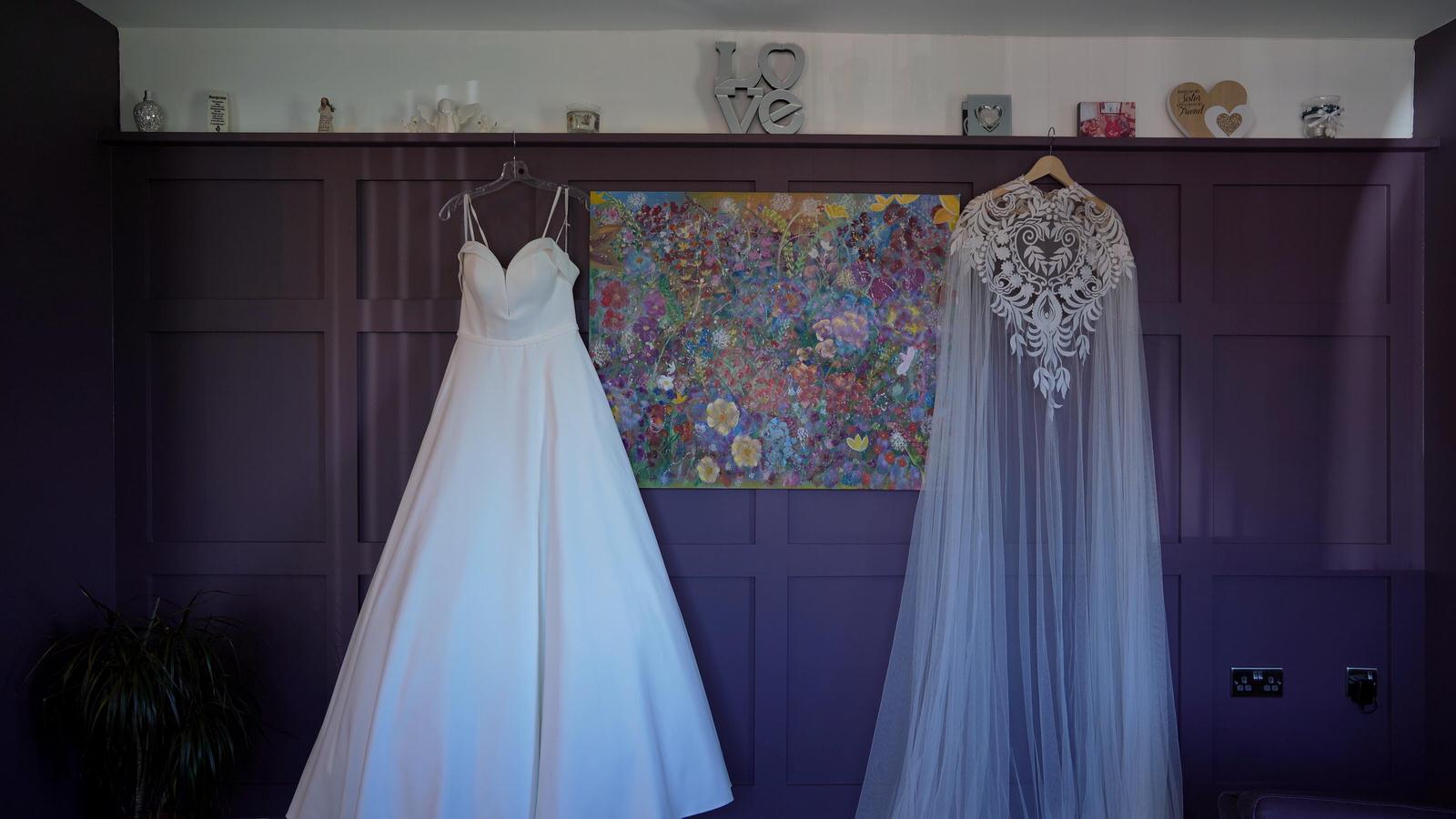 a wedding dress and cape hang waiting for a bride