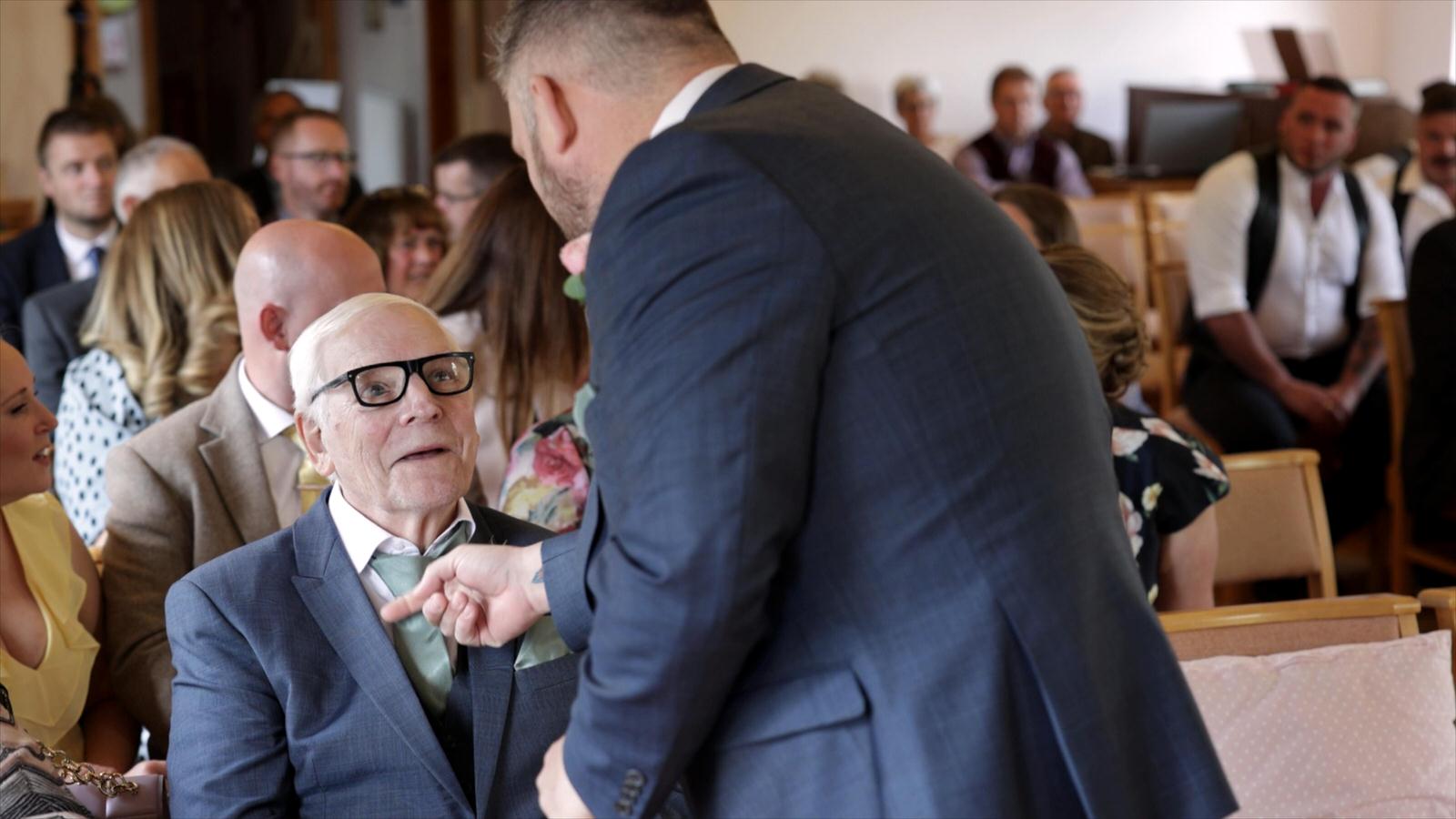 the groom fixes his dads tie in church