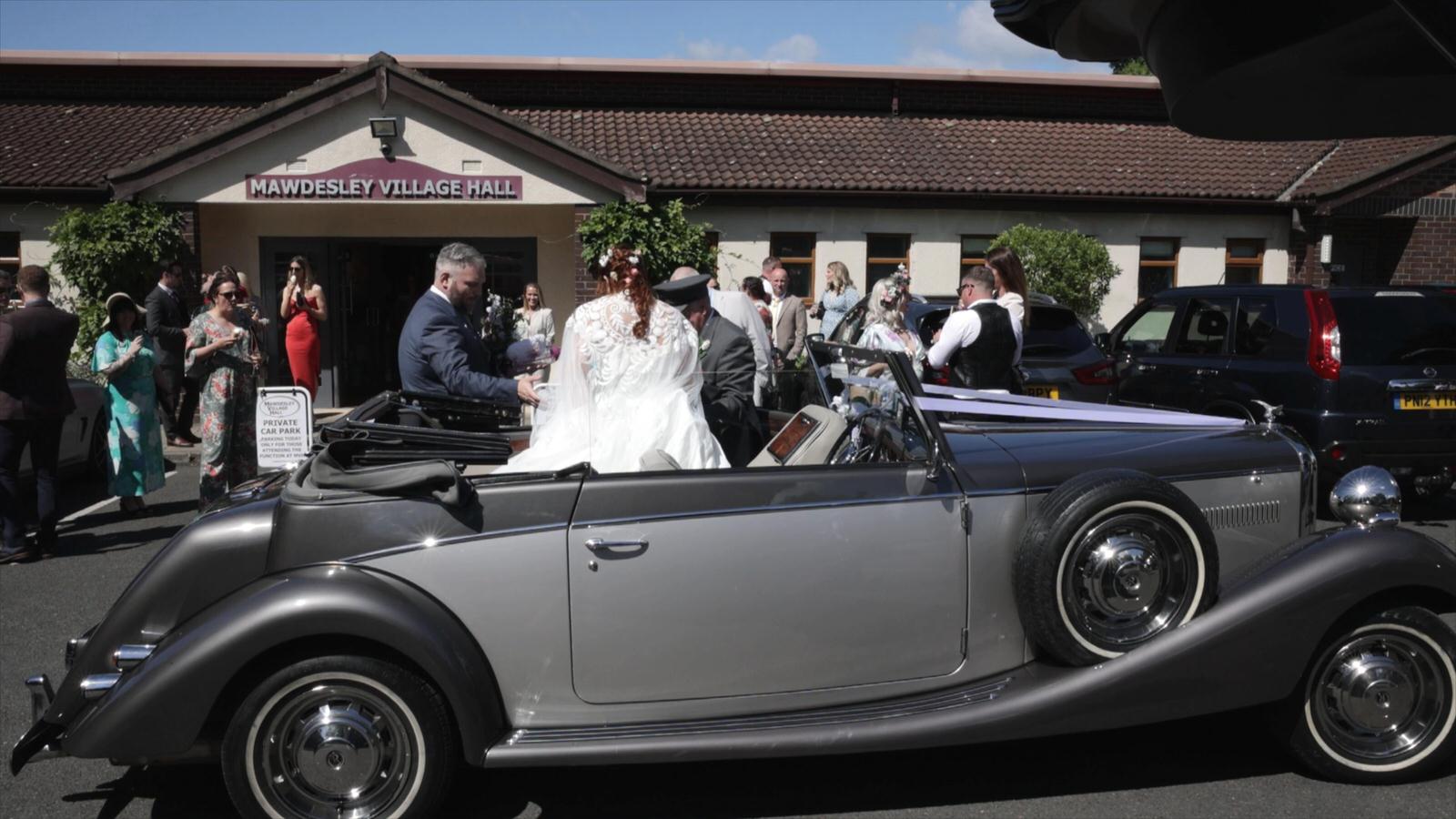 bride gets out of Malvern wedding car outside Mawdesley village hall