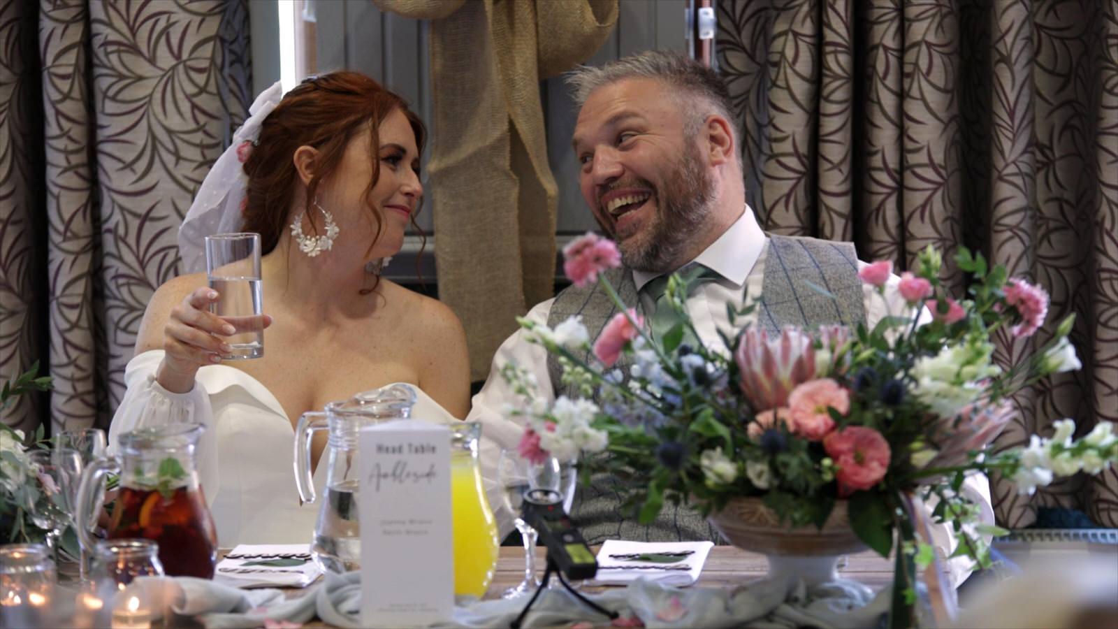 the bride and groom laugh during speeches at Mawdesley village hall