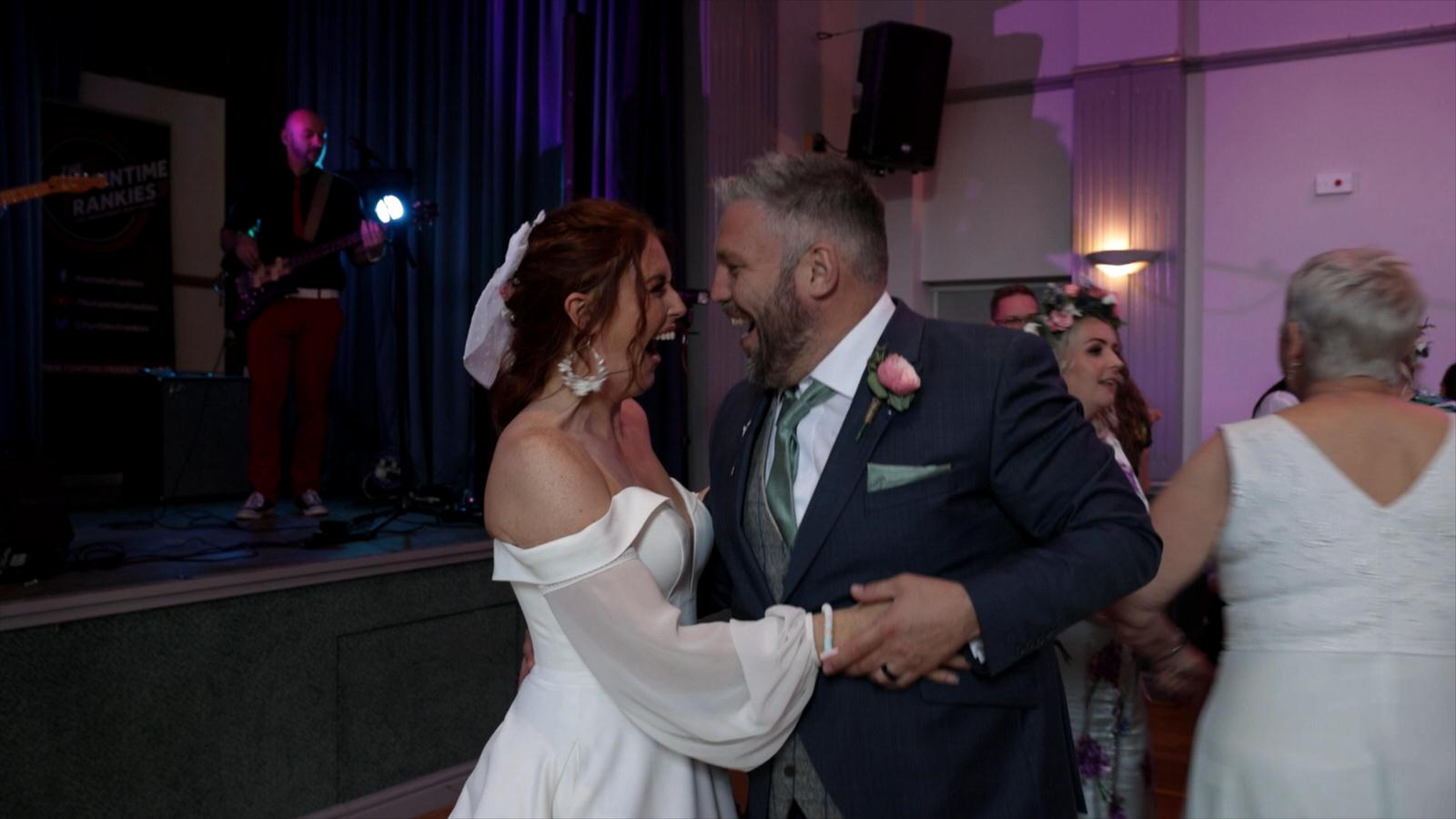 couple laugh at each other dancing to the wedding band