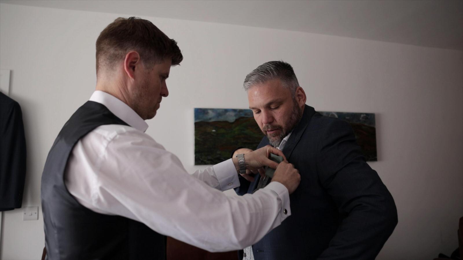 the groom has help with his button hole
