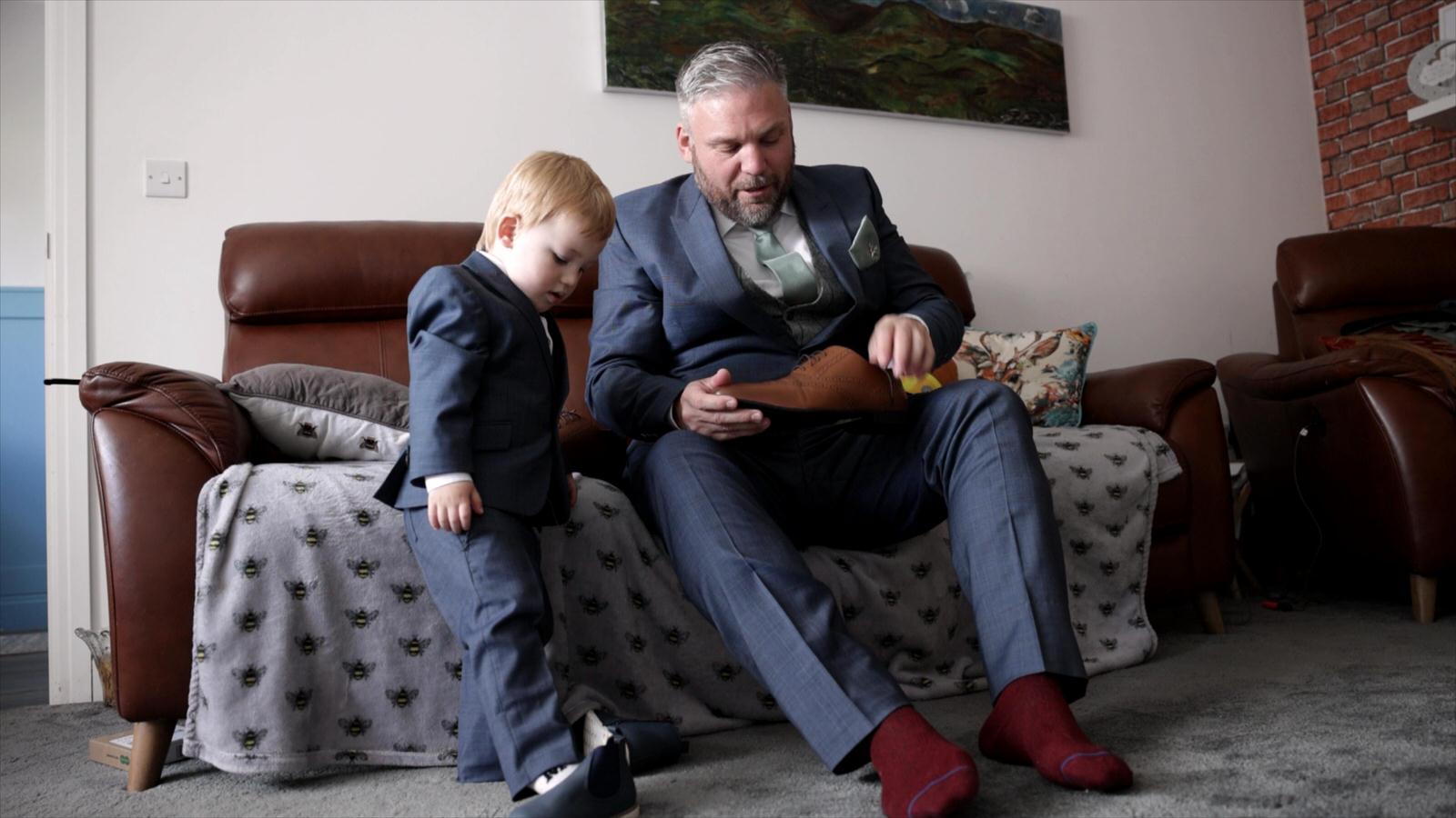 a son copies his dad putting wedding shoes on