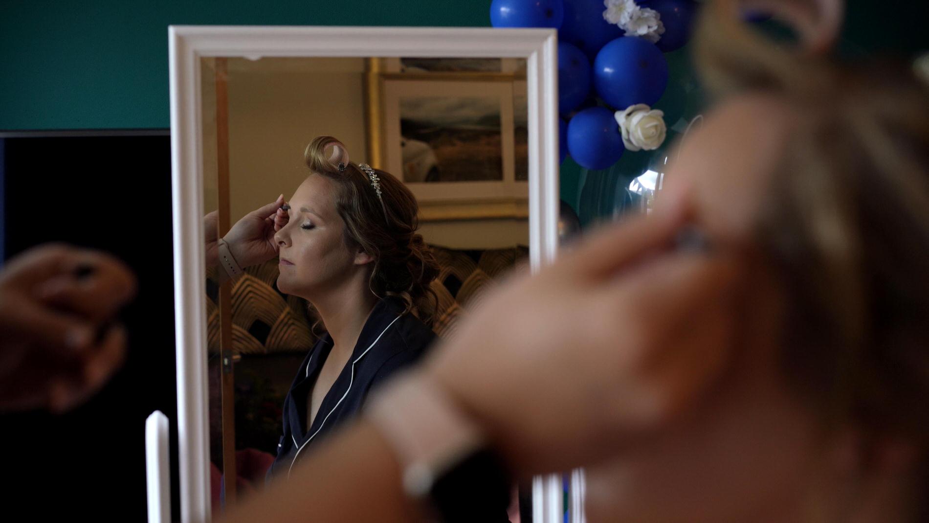 brides reflection in mirror having makeup done