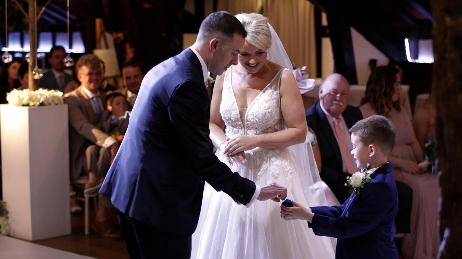 page boy gives wedding rings during ceremony at Rivington hall barn