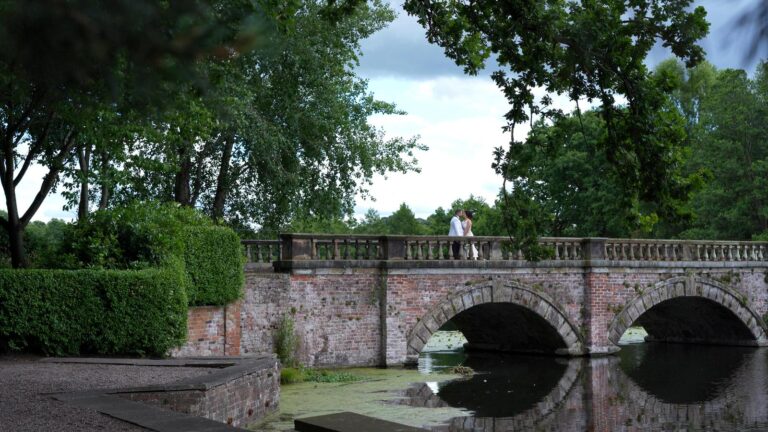 video still of bride and groom on lake bridge at Capesthorne