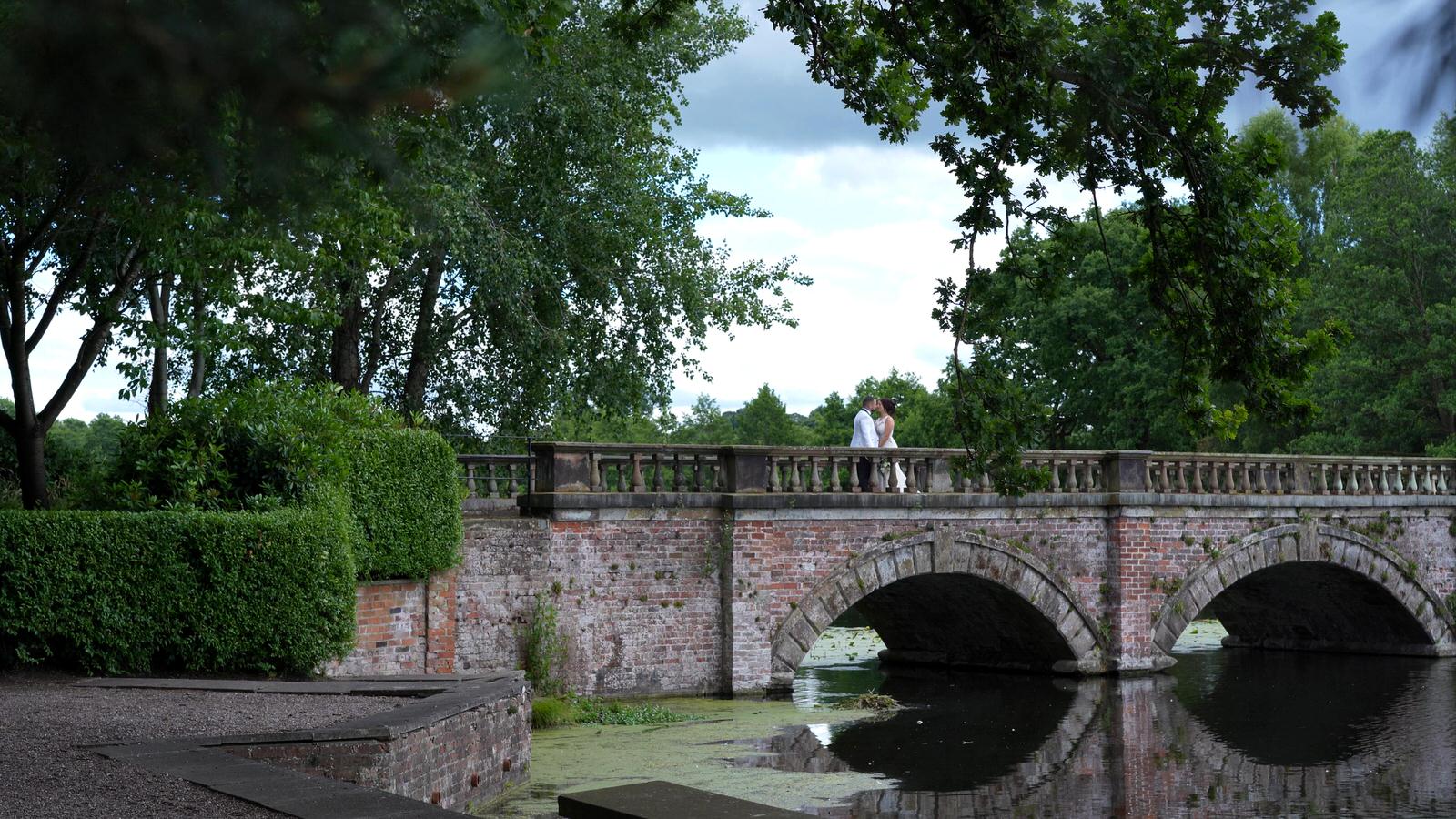 video still of bride and groom on lake bridge at Capesthorne