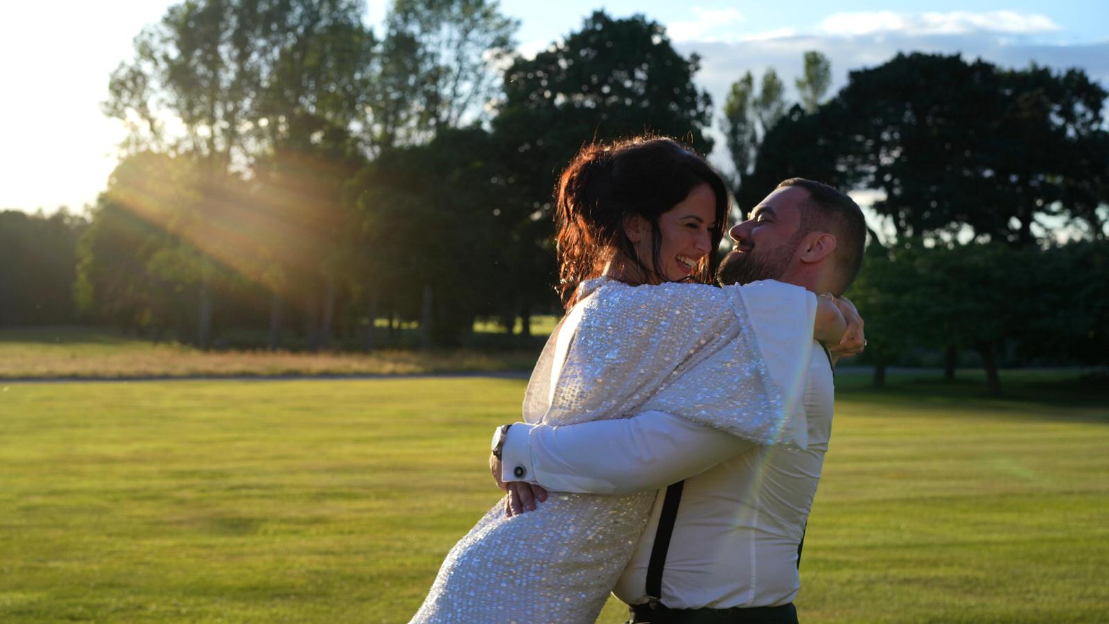 groom picks bride up during filming at Capesthorne hall
