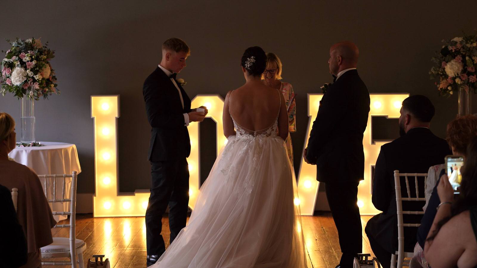 son and best man holds out wedding rings during ceremony