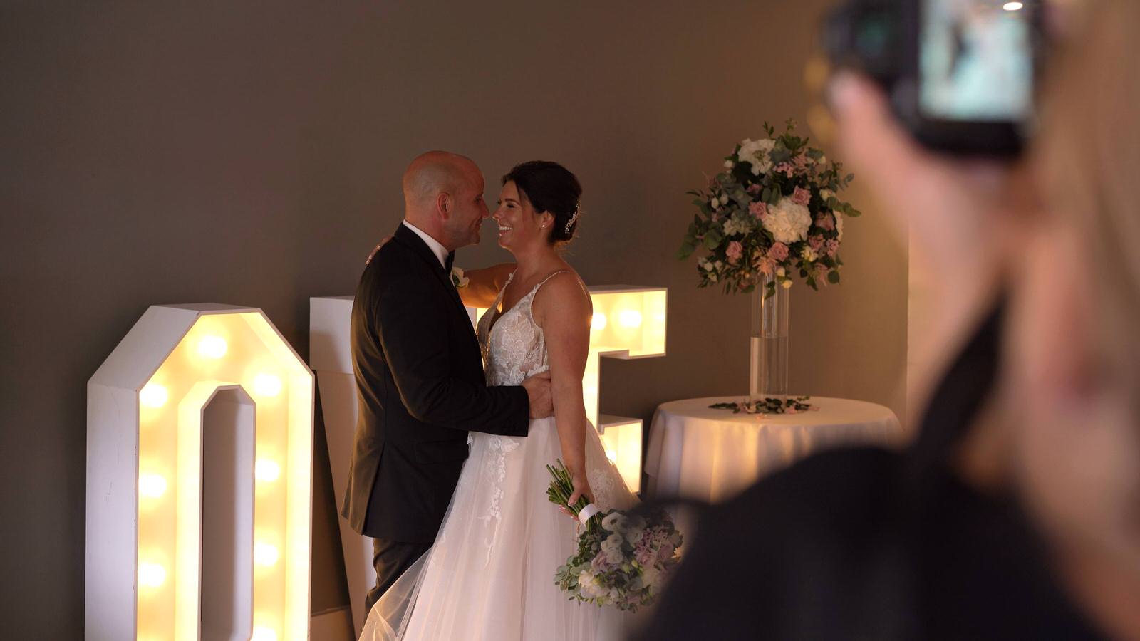 Photographer takes photo of couple in front of LOVE letters