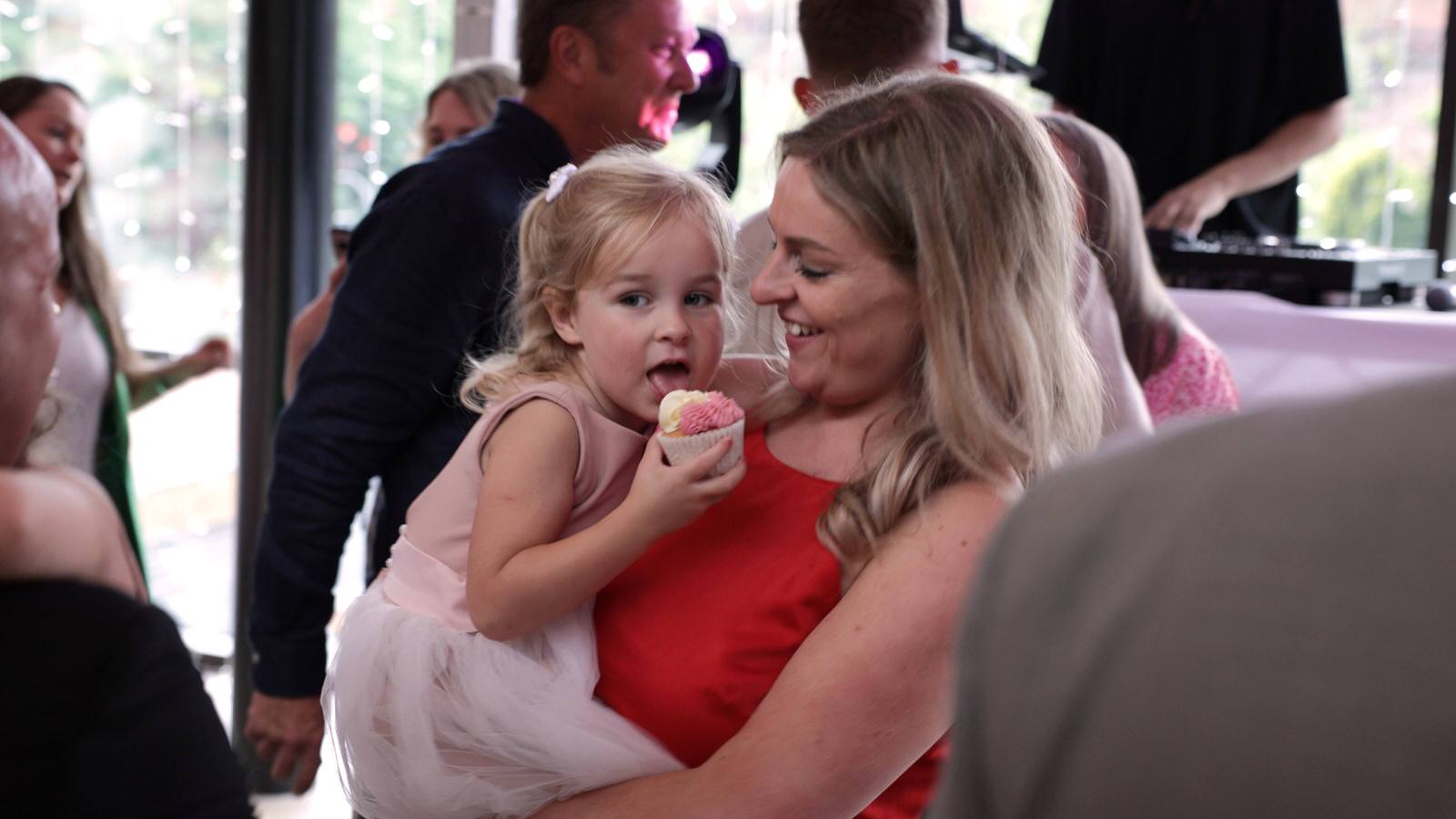 flower girl licks a cupcake whilst dancing