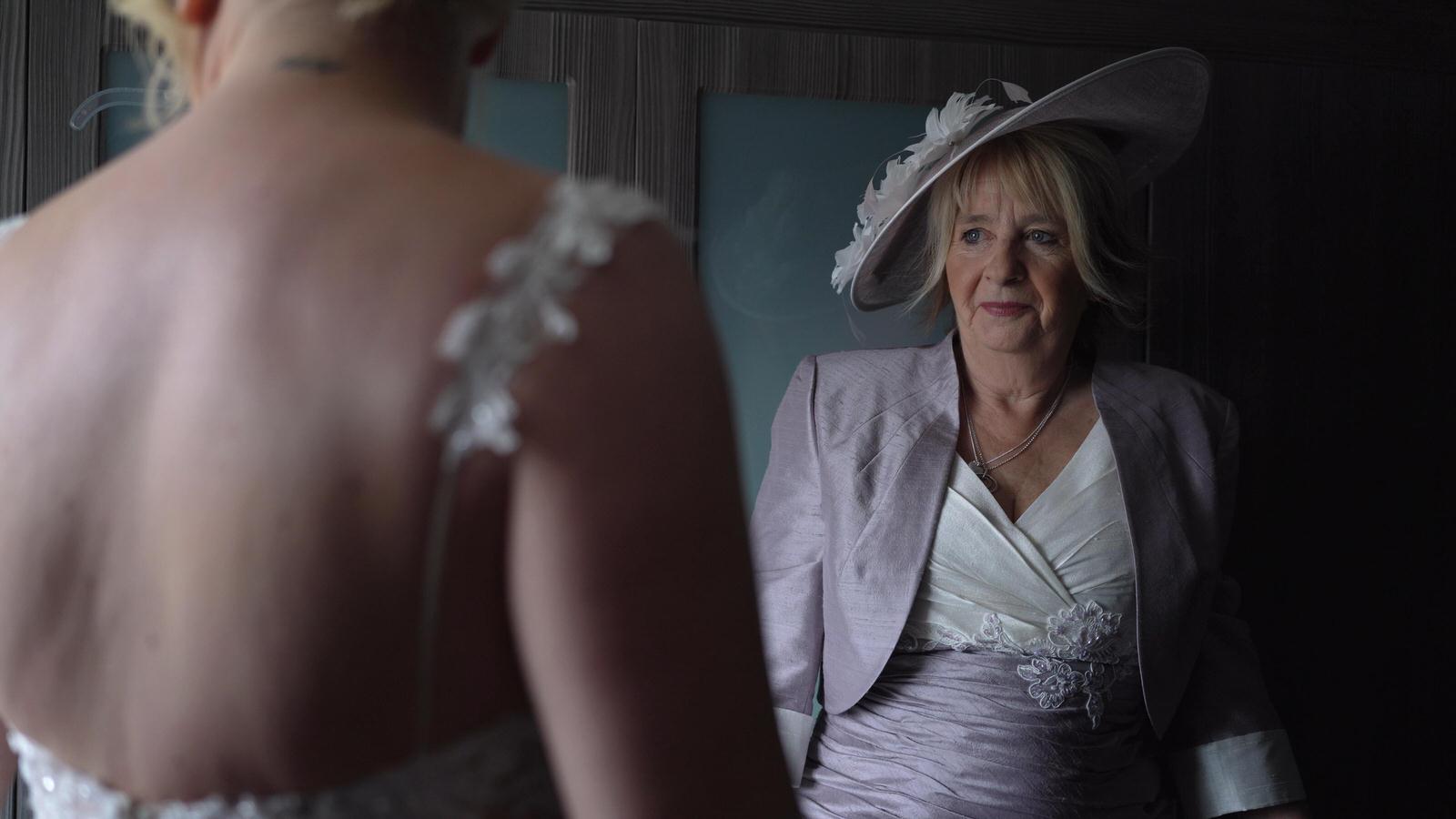 mother of the bride looks on as bride gets ready