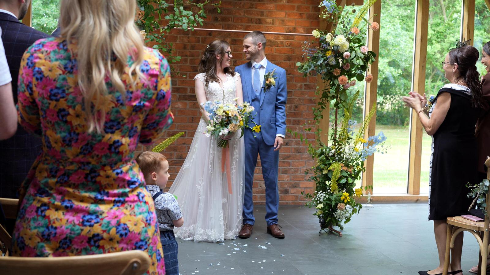 couple grin at each other before walking down the aisle
