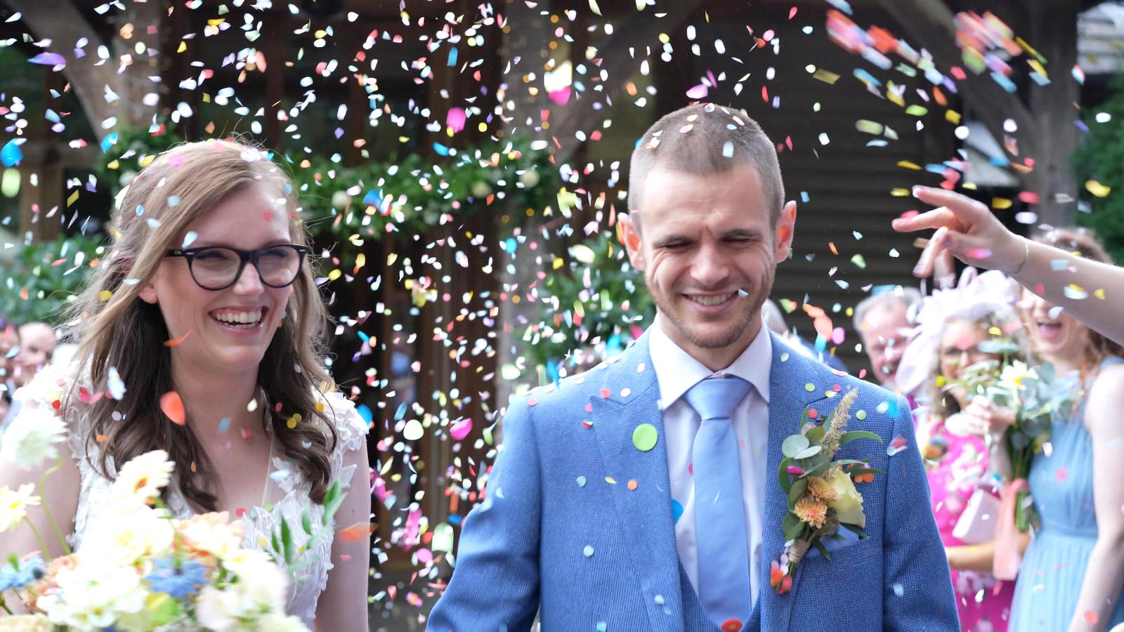 couple showered in rainbow confetti outside oaktree of peover