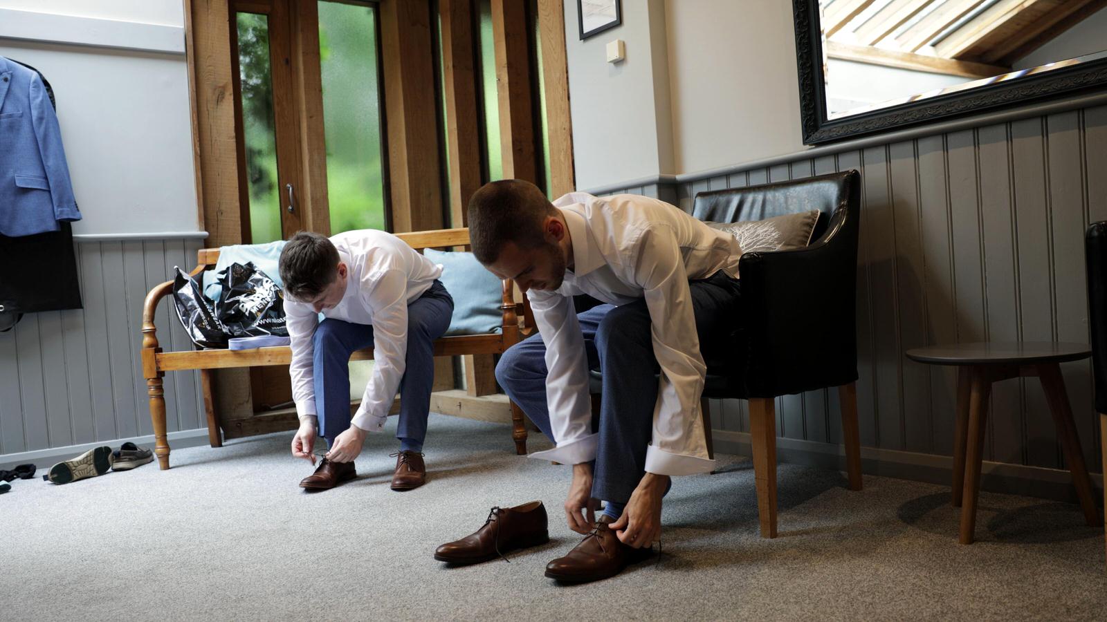 groom and best man put their wedding shoes on