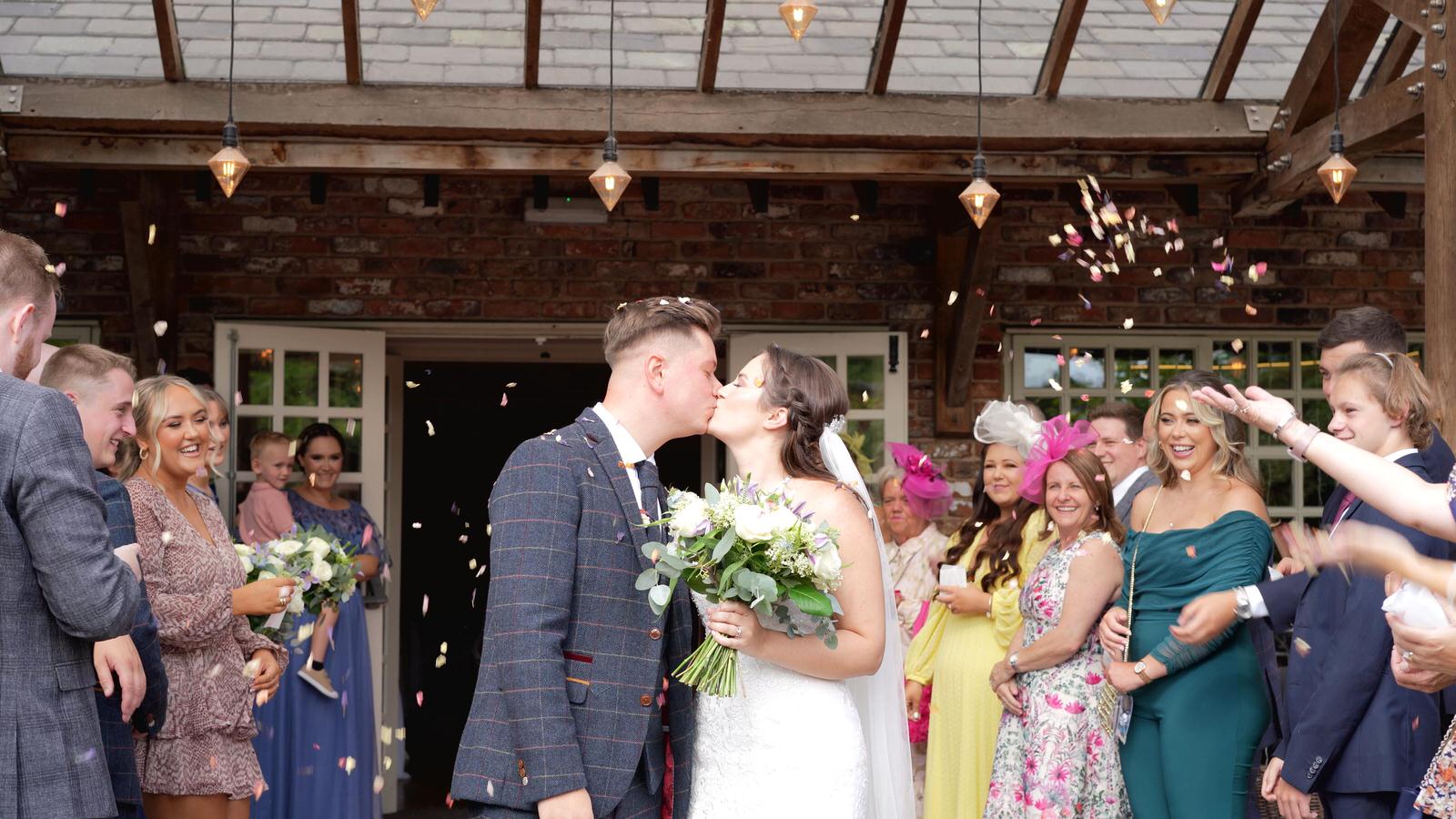 a couple kiss outside Charnock Farm during a confetti shot