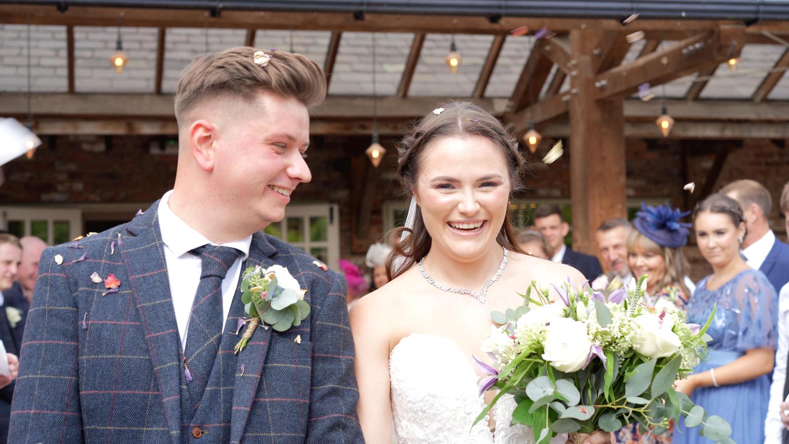 a couple smile at the videographer during confetti