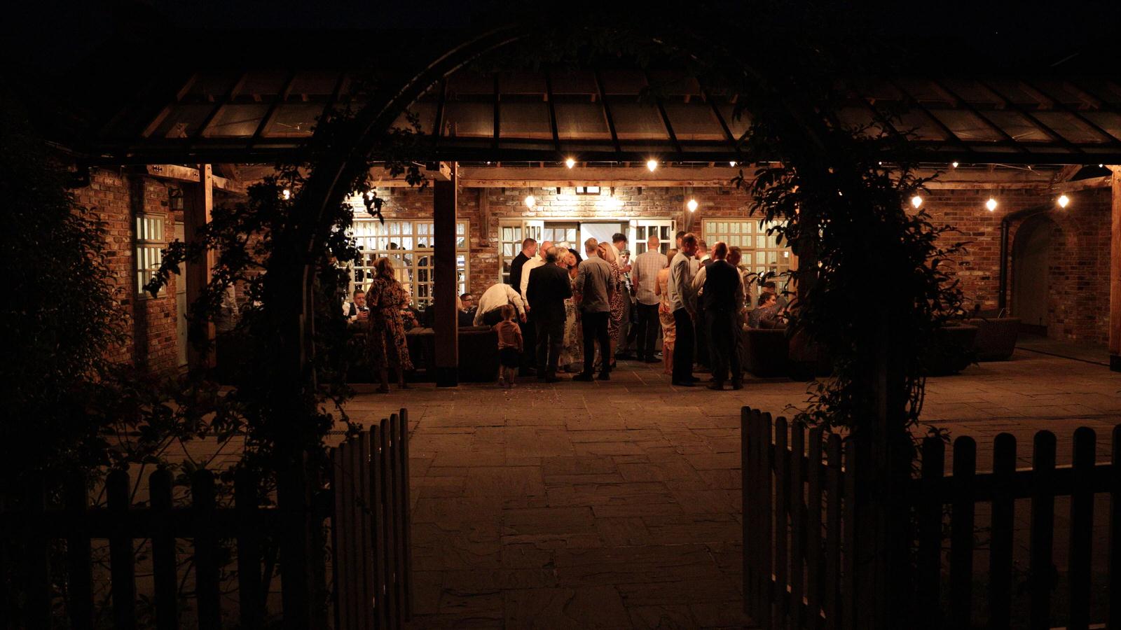 late evening shot of guests drinking outside Charnock Farm wedding