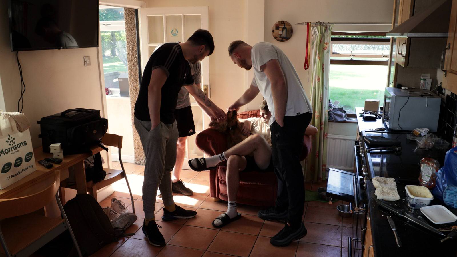 groomsmen fuss over farm dogs in kitchen