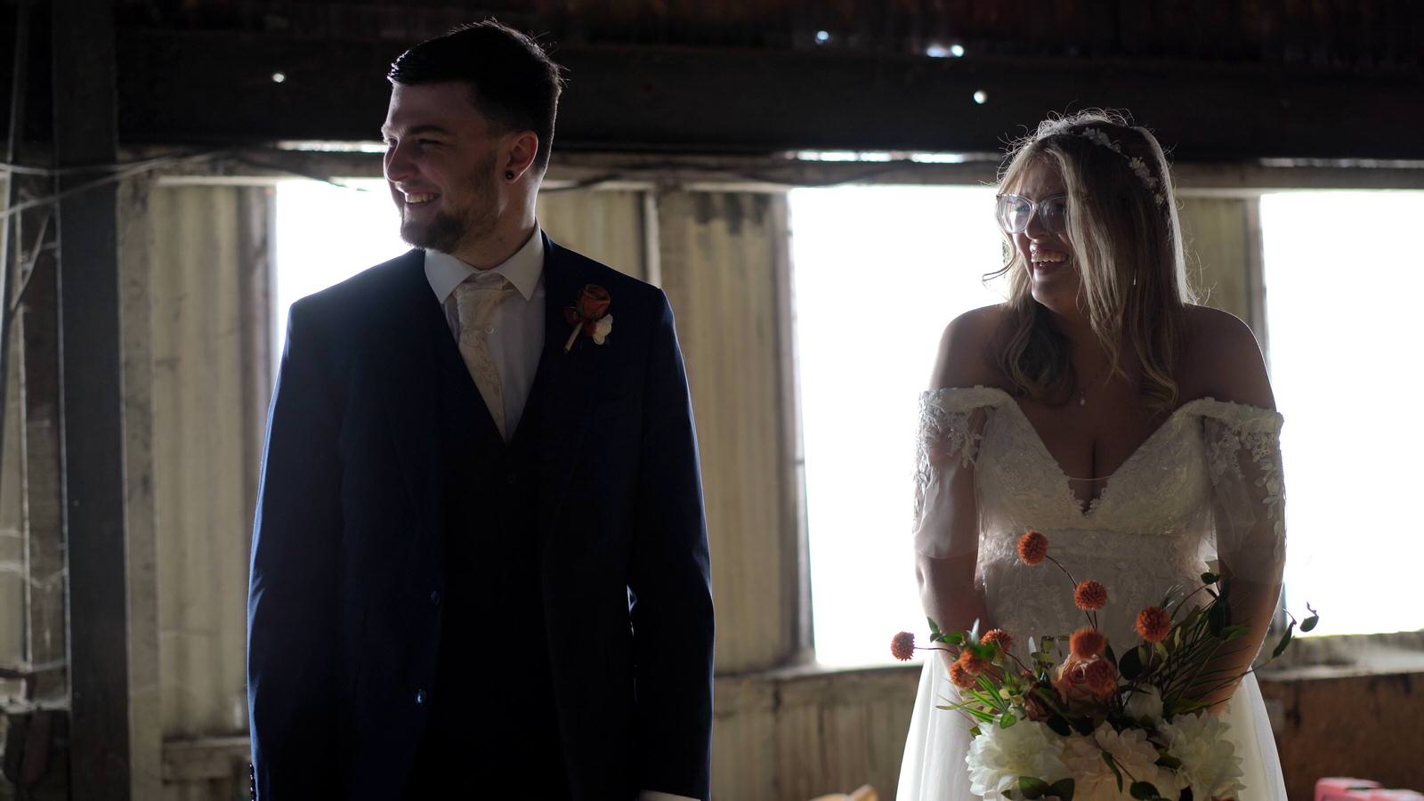 couple pose for photographer in a barn
