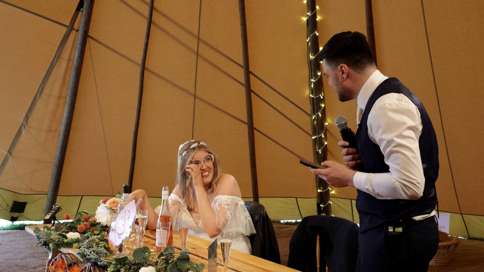 bride wipes away tears during Grooms wedding speech
