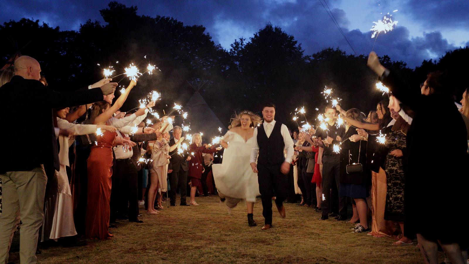 couple run towards the camera during sparkler shot