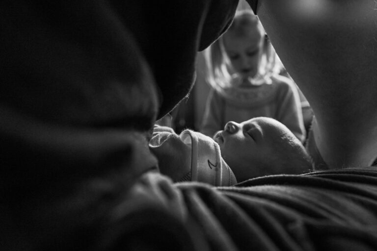 creative natural photo of newborn baby through his Dads arms at home