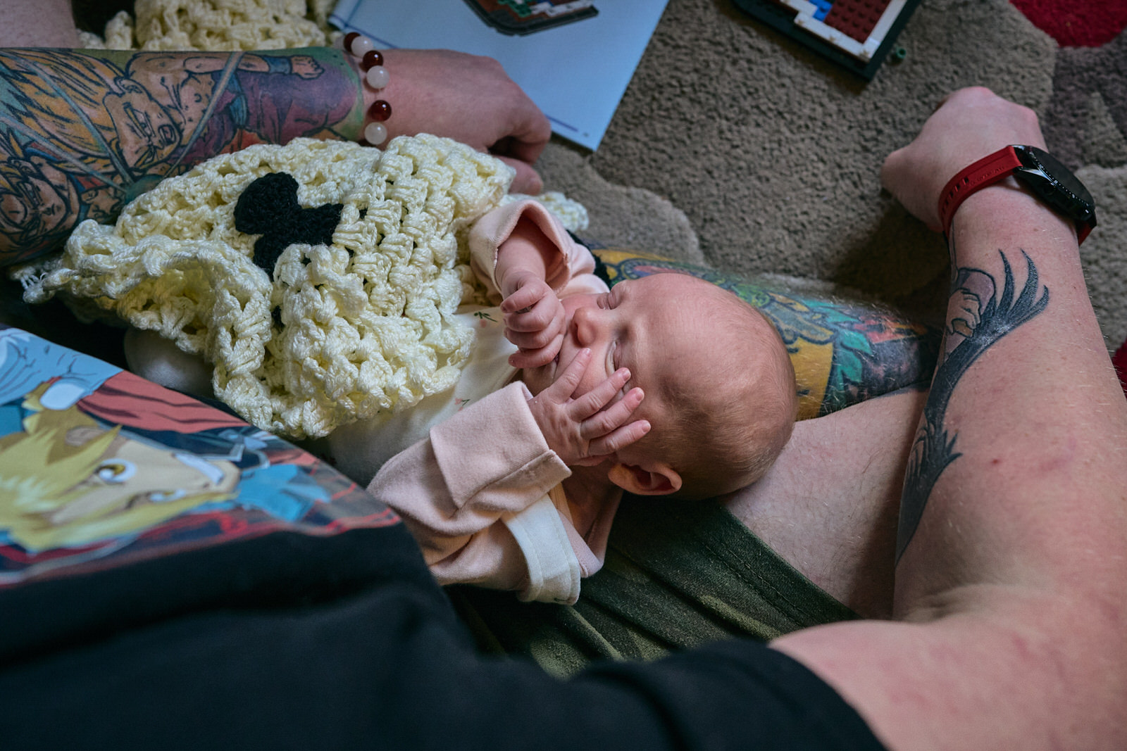 newborn baby lays on Daddys knee