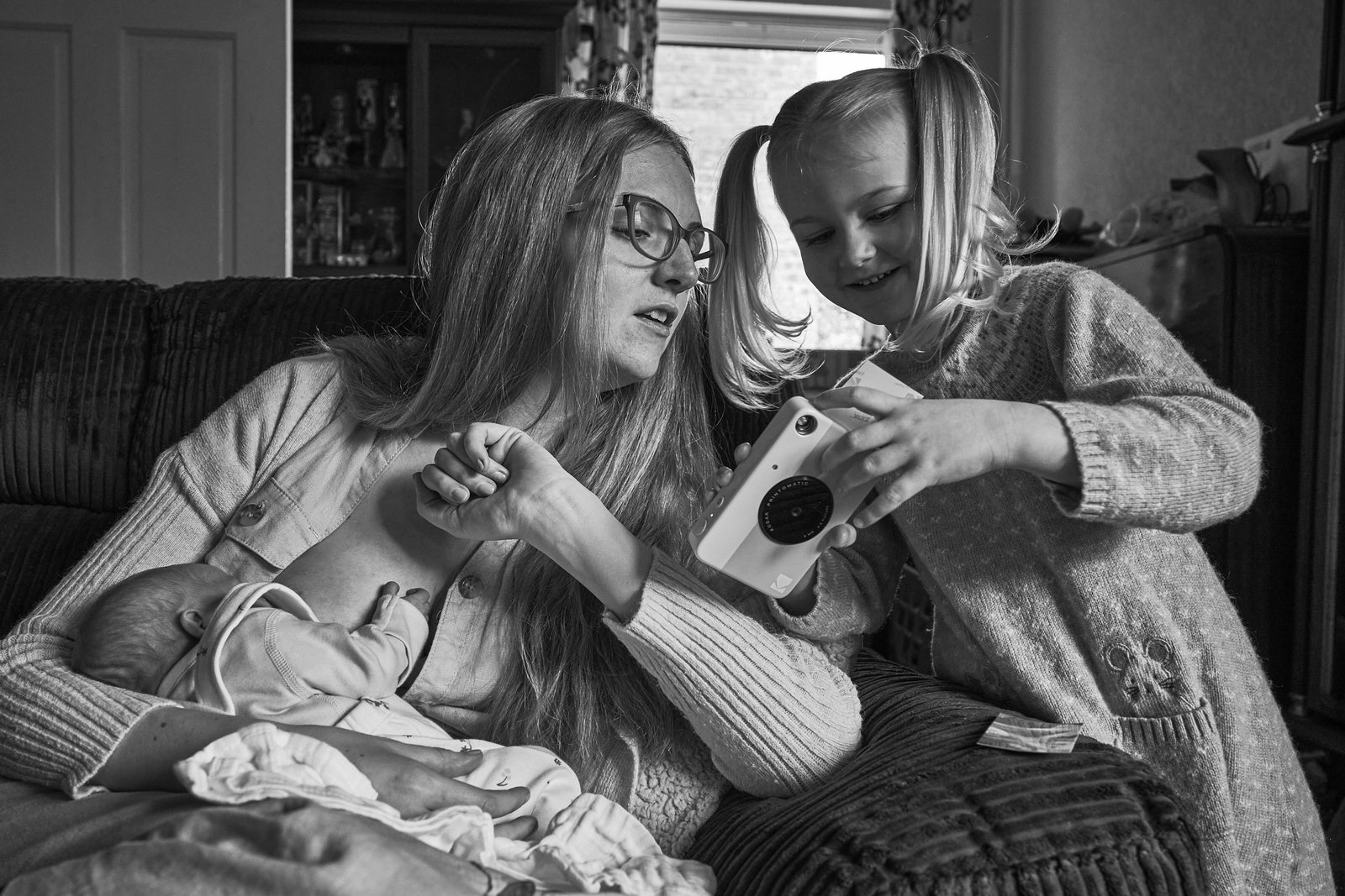 mum looks at daughters photo with her polaroid camera