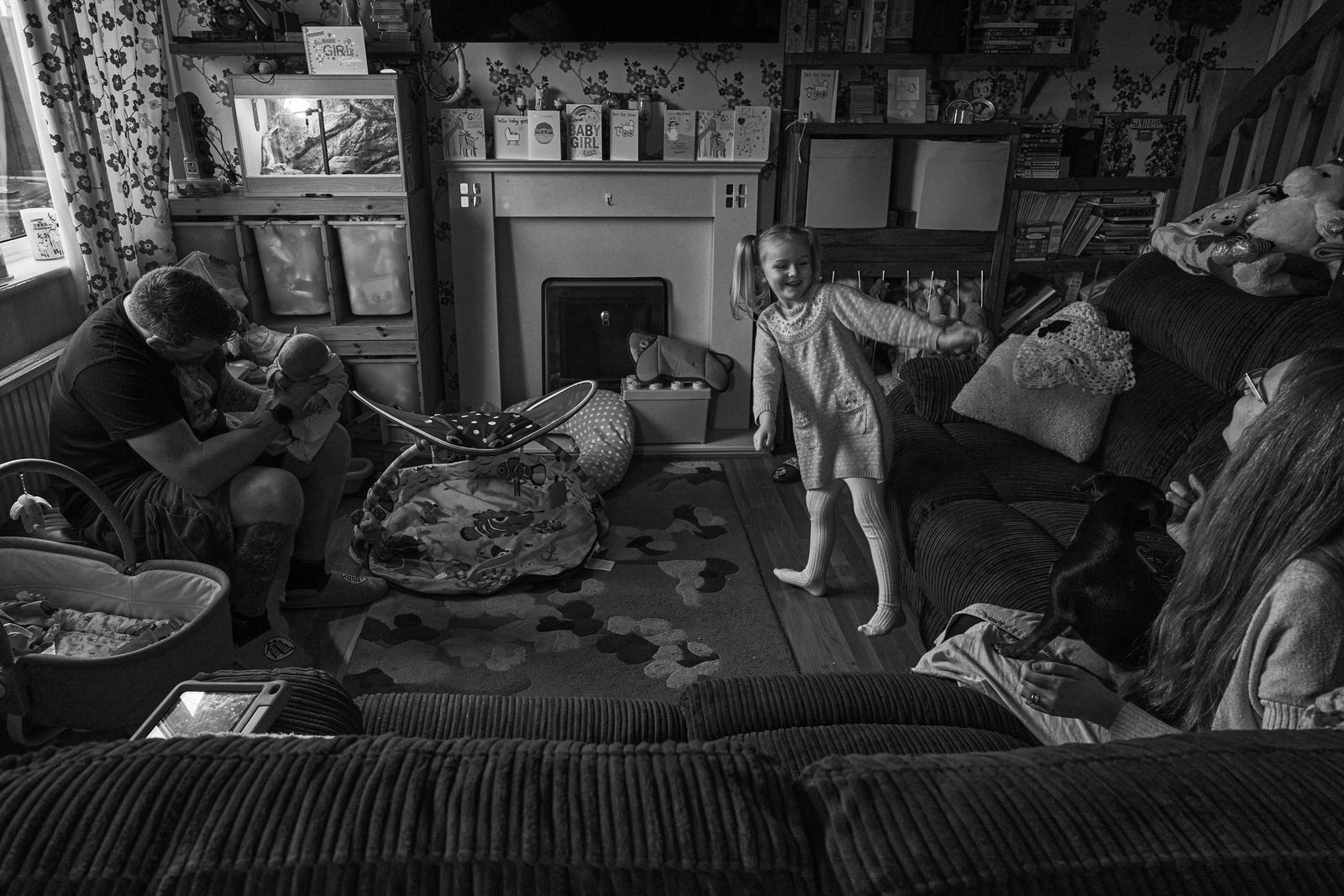 wide photo of a family living room with a 10 day old baby and older sister