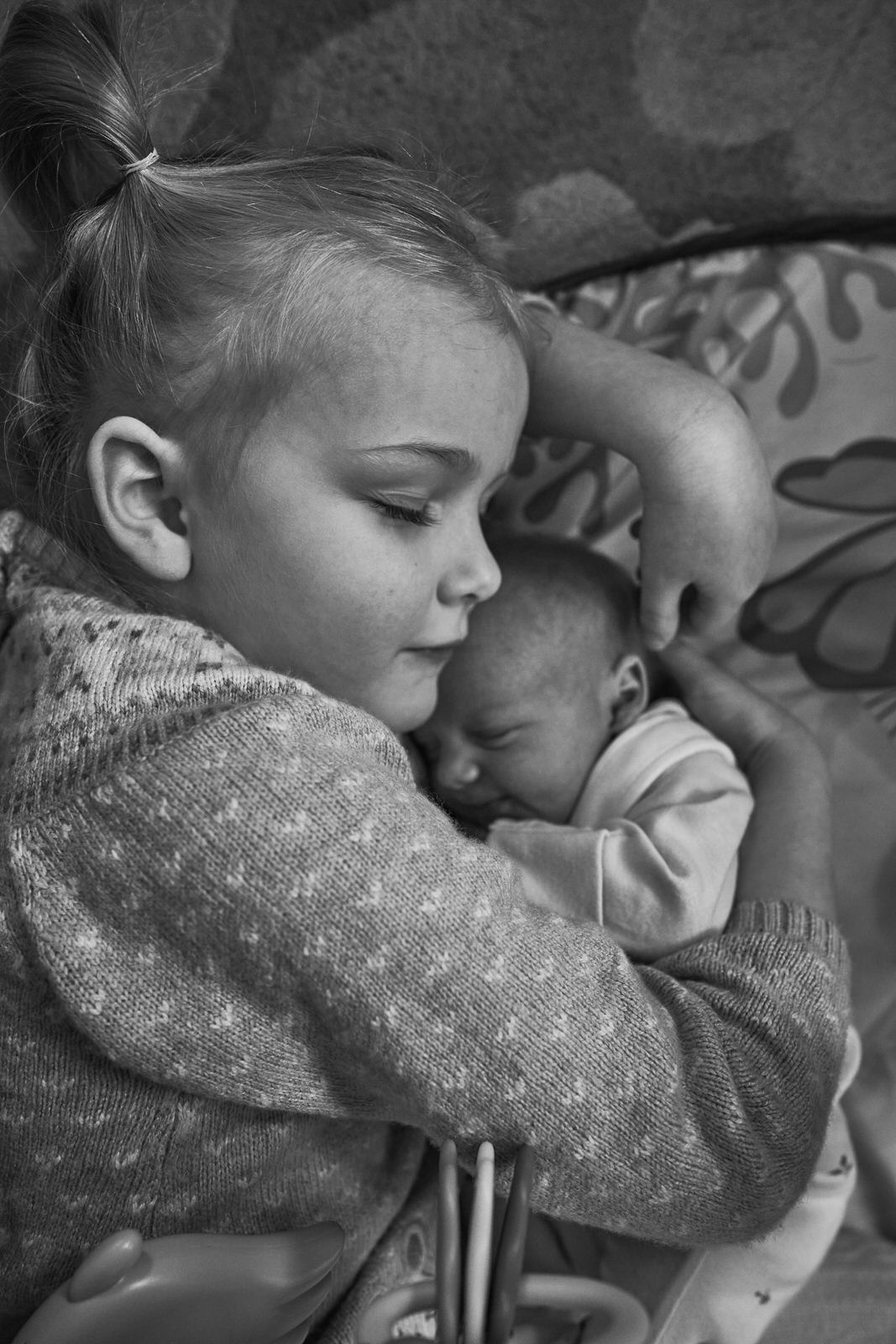 natural black and white photo of older sibling cuddling baby