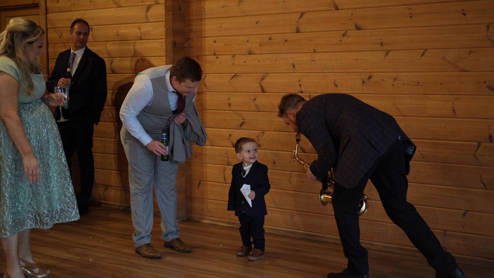 saxaphone player Mike Smith entertains page boy during drinks reception