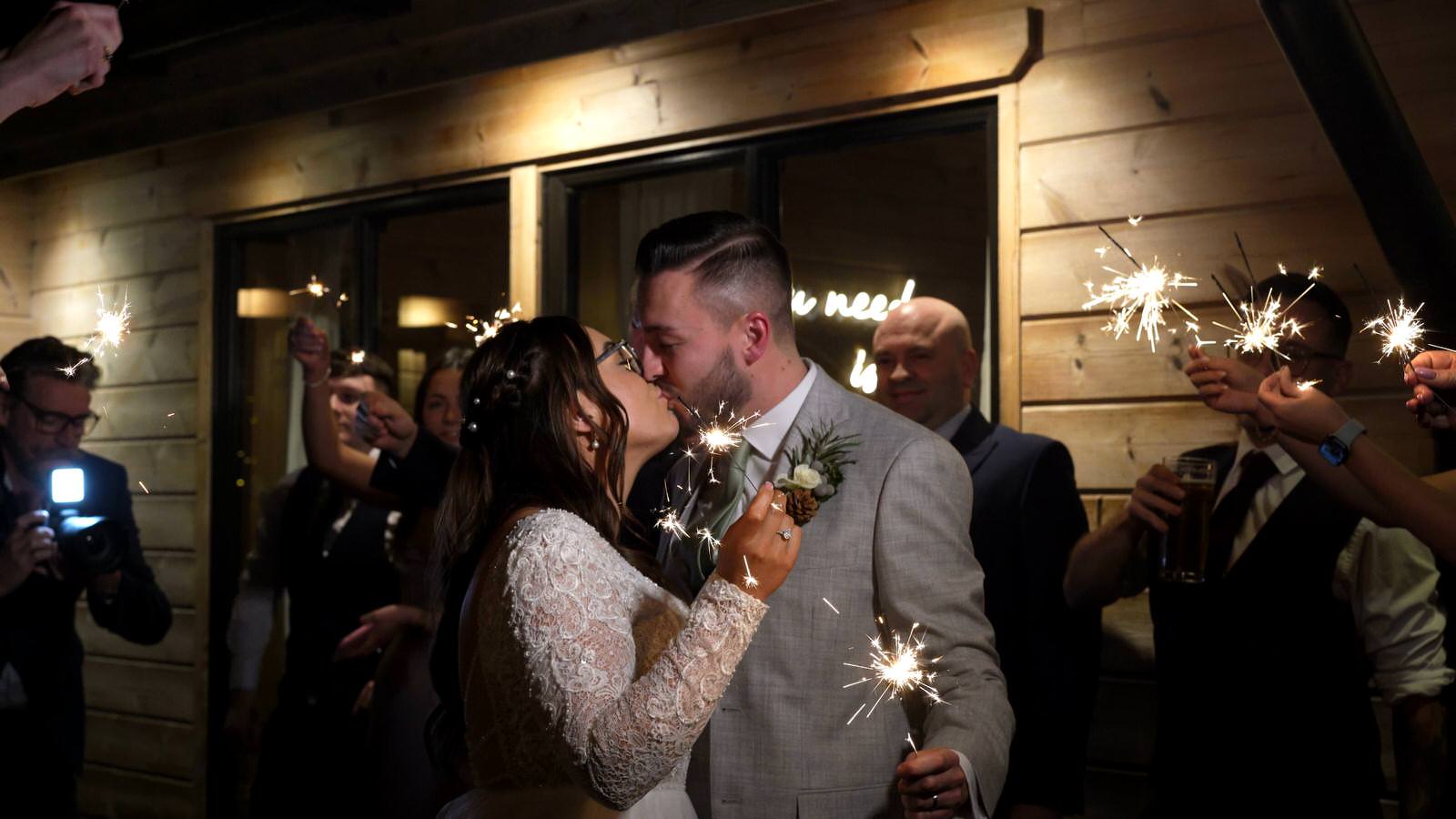couple kiss during sparklers outside Styal Lodge
