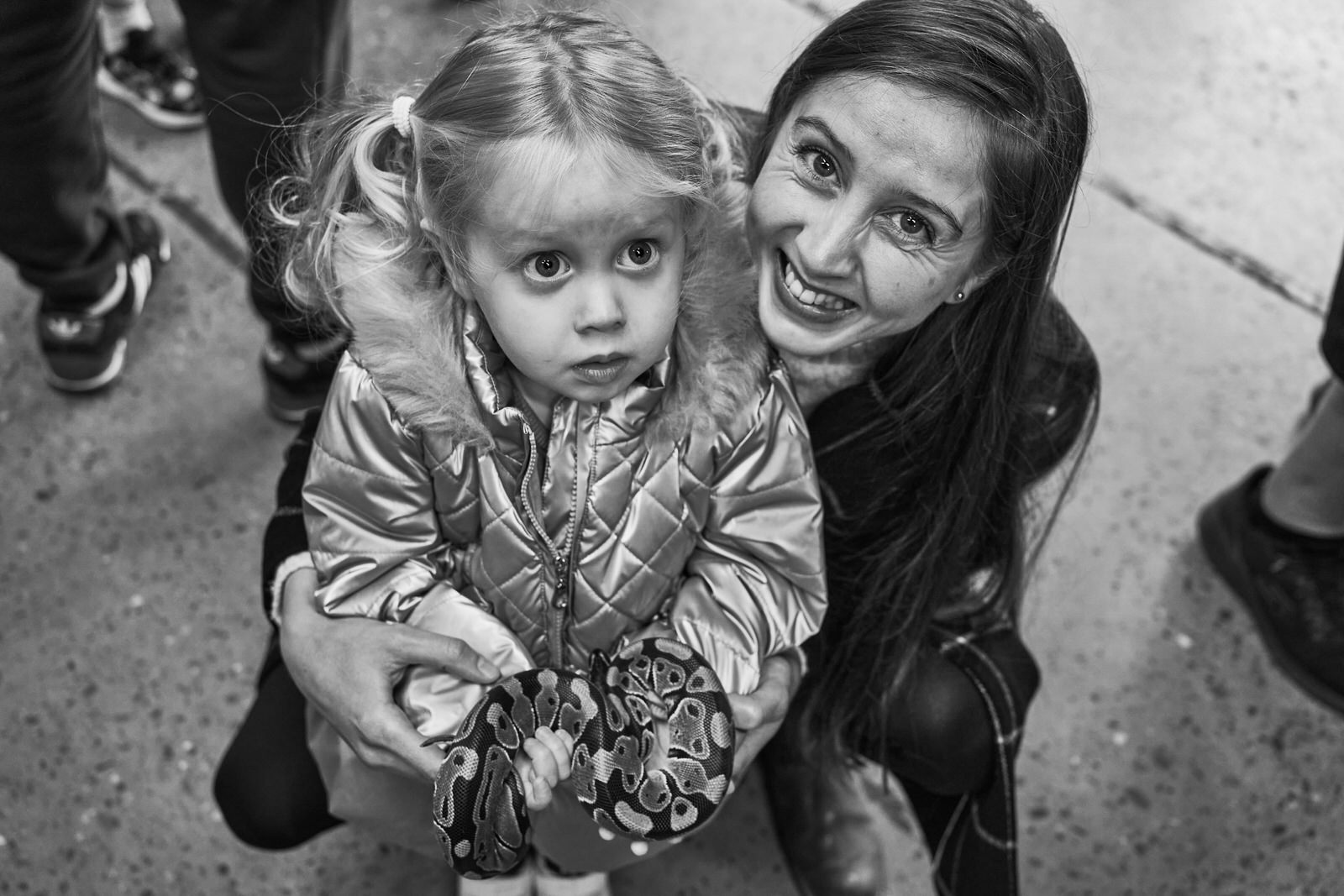 a mum looks up at the camera as her daughter holds a snake eyes wide