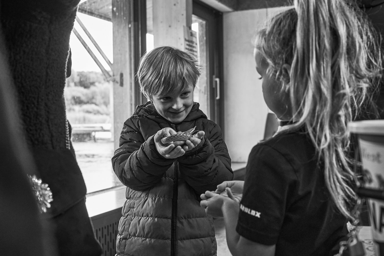 a boy smiles as he holds a snake with a NW reptile club member