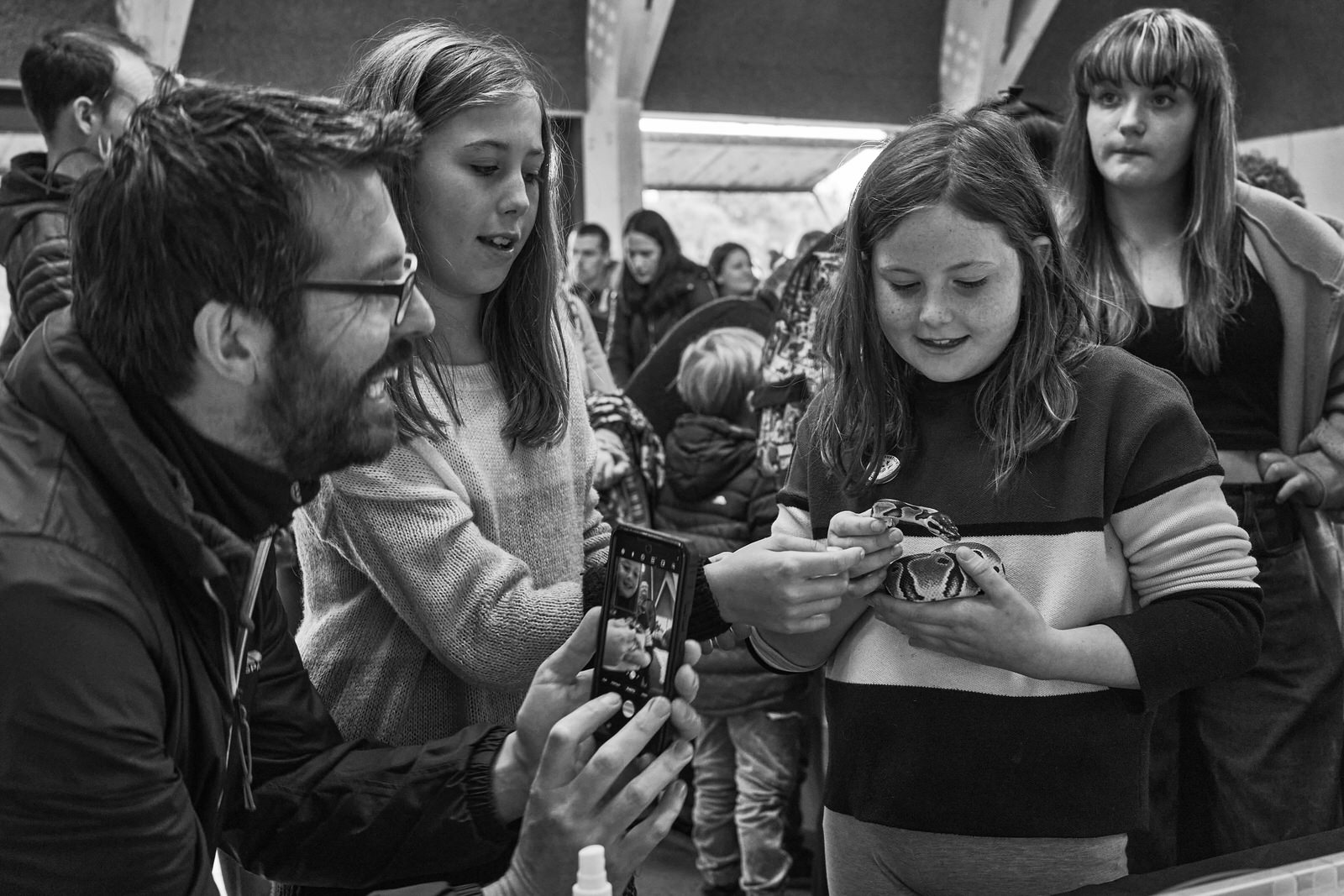A young girl holds a reptile as dad takes a photo