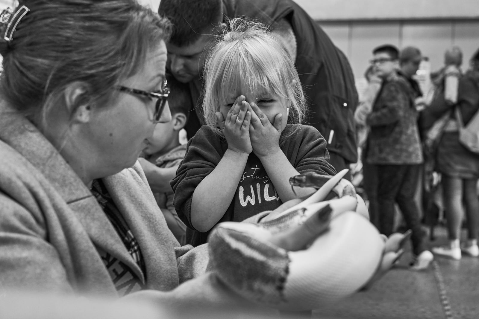 a child covers her face with excitement as she's shown a snake