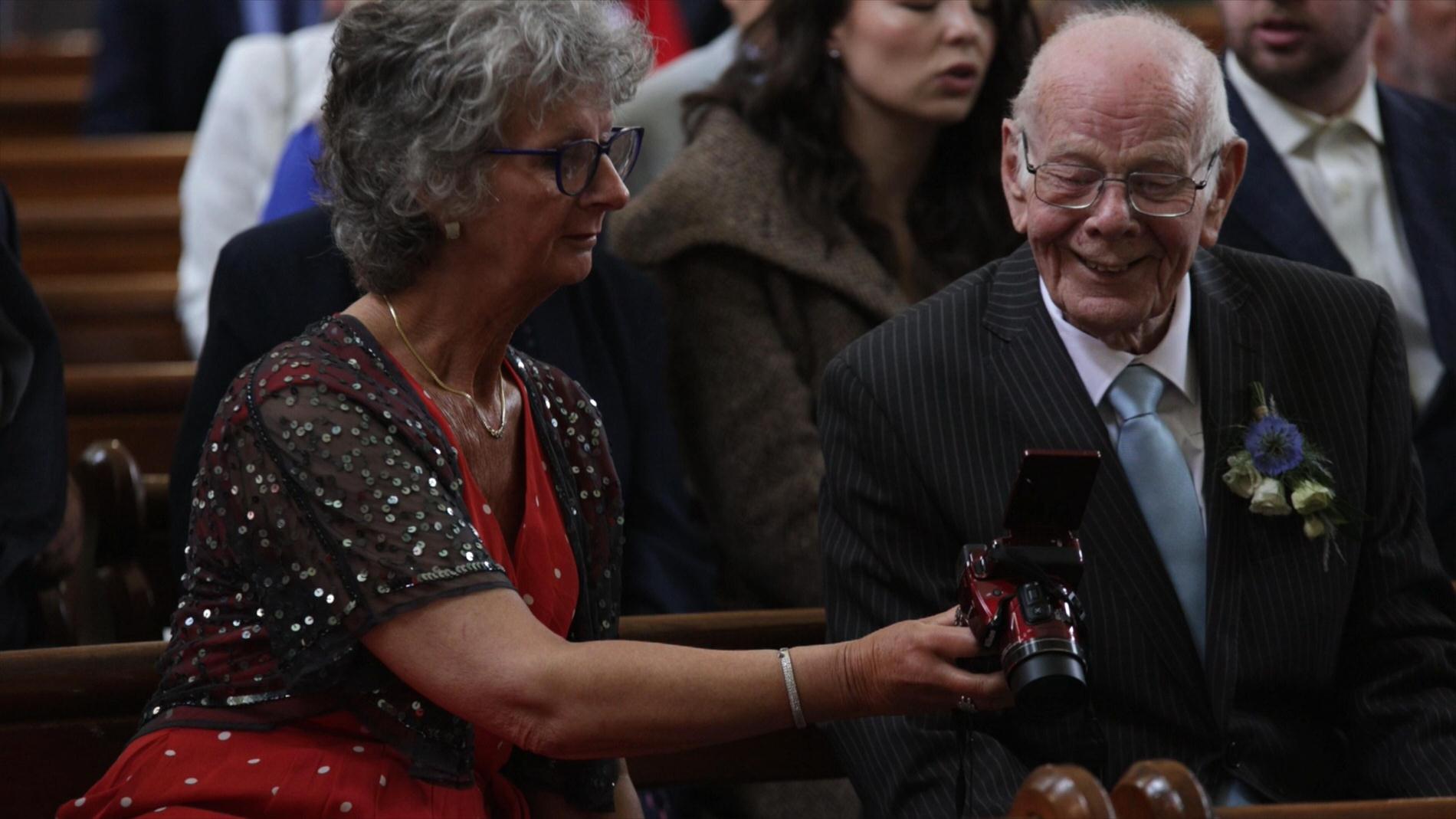 two guests laugh at a photo on the back of a camera