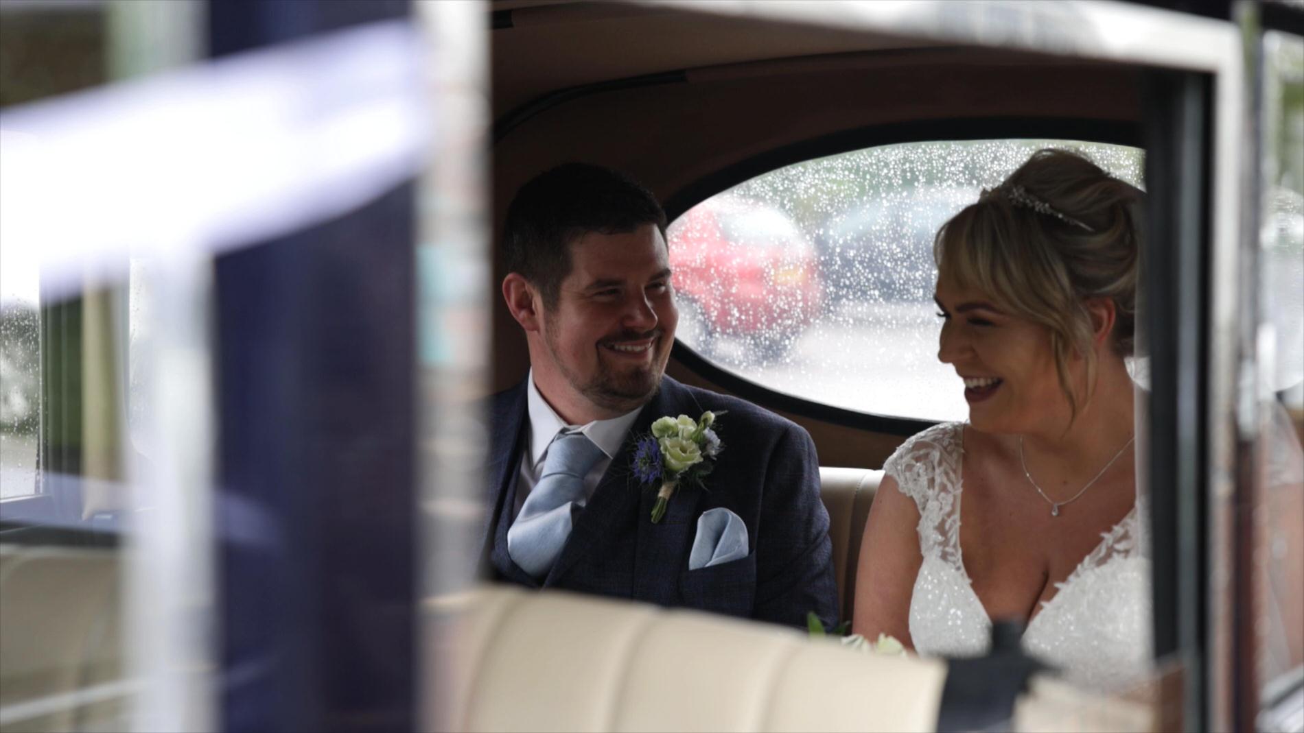 the couple laugh inside the wedding car