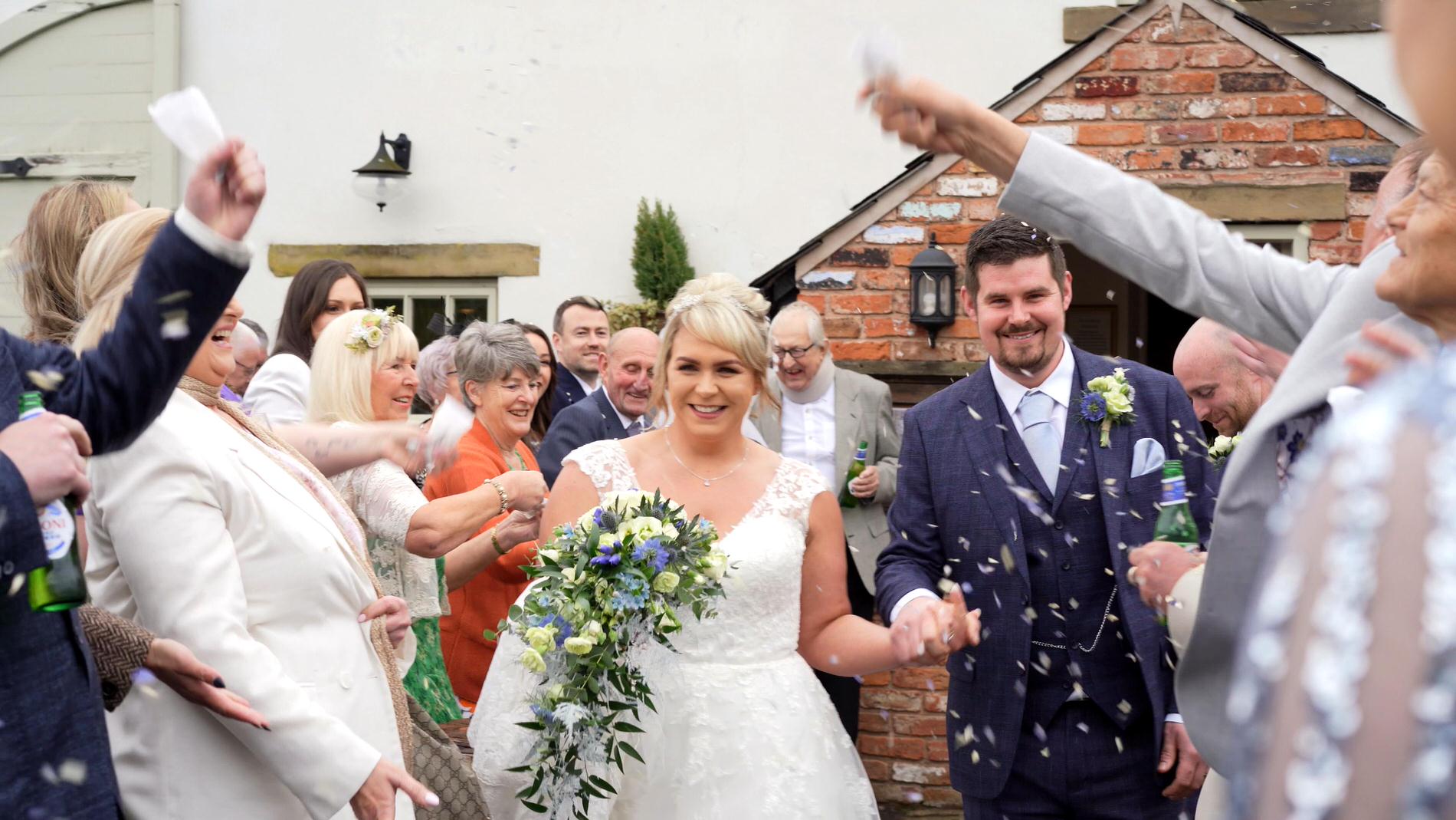 a couple are showered in confetti outside Charnock Farm