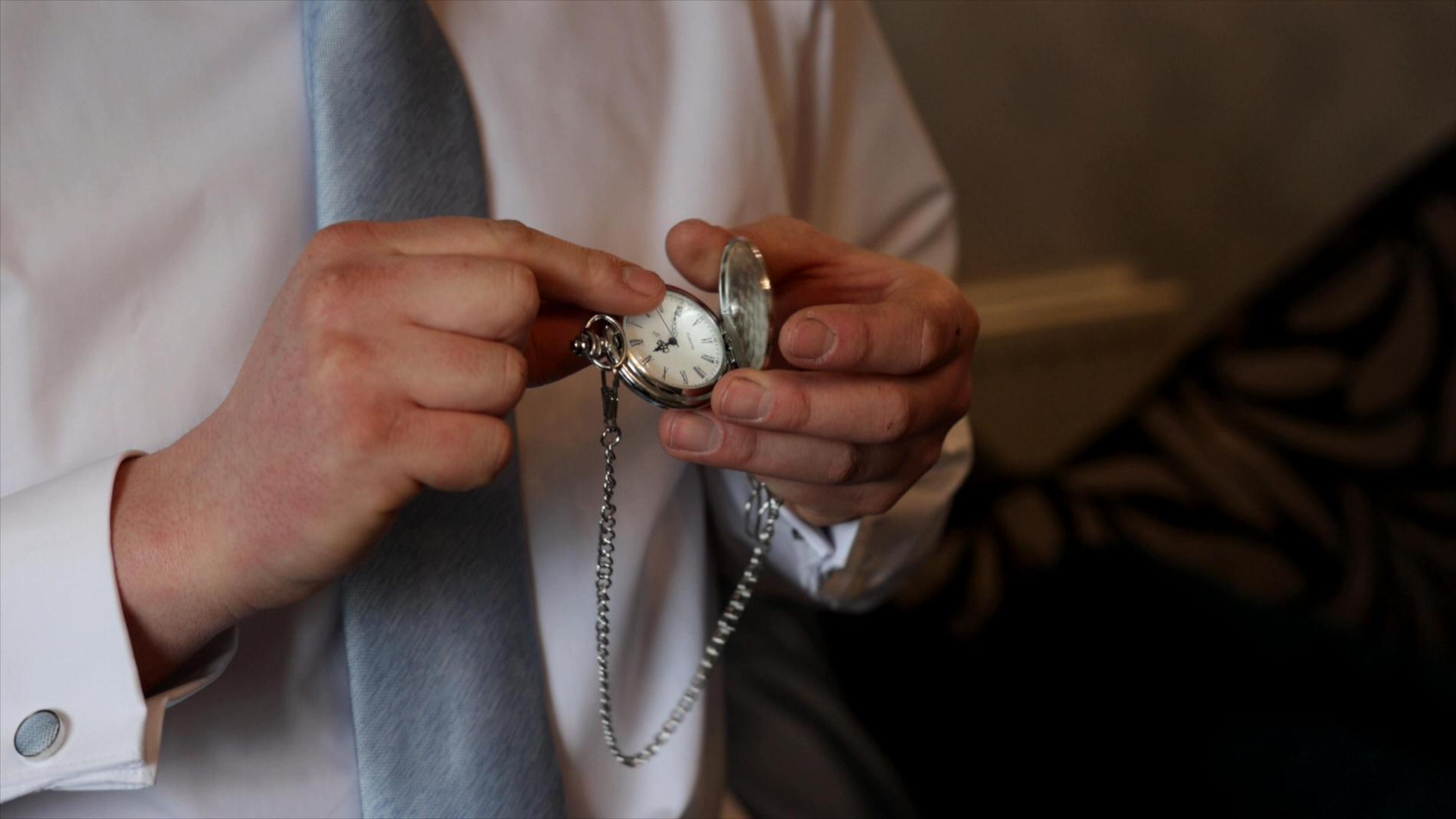 a groom plays with his new pocketwatch