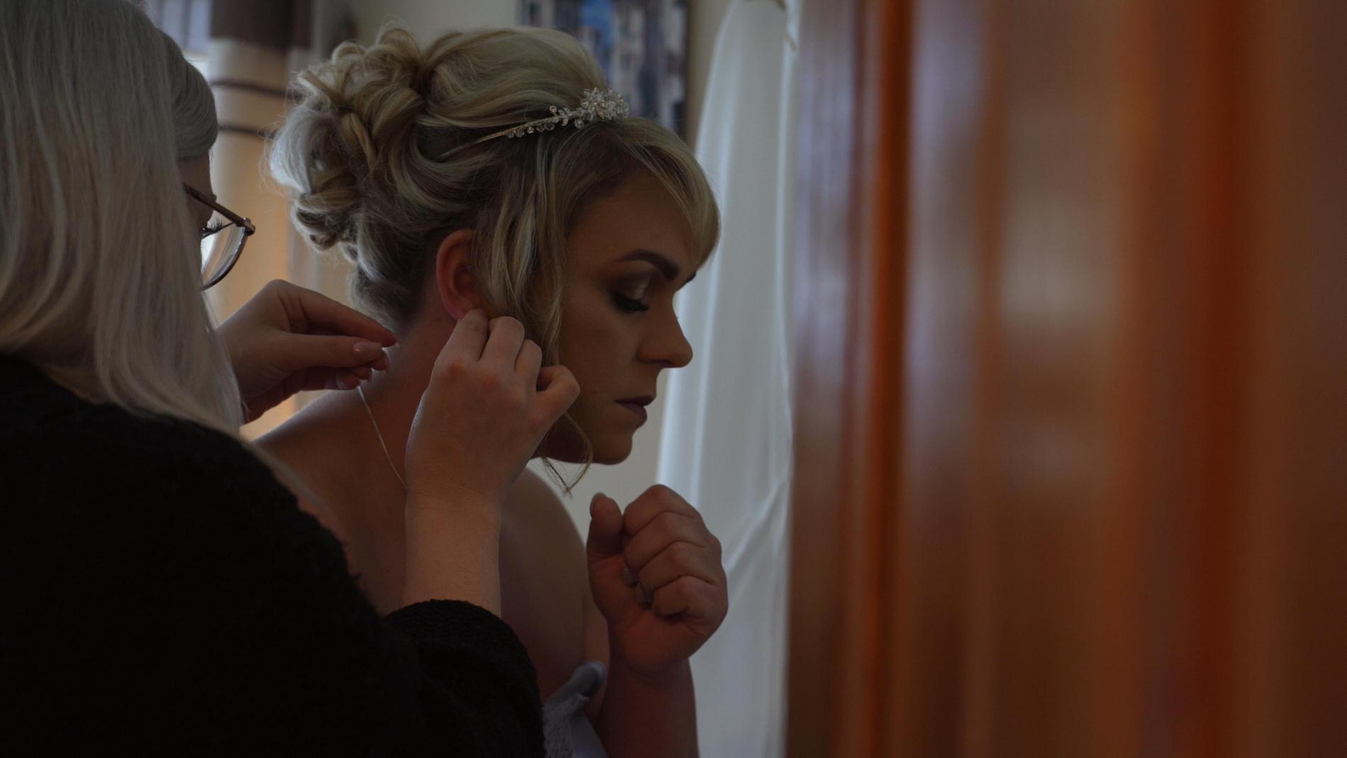 a bride has someone put her wedding earrings in